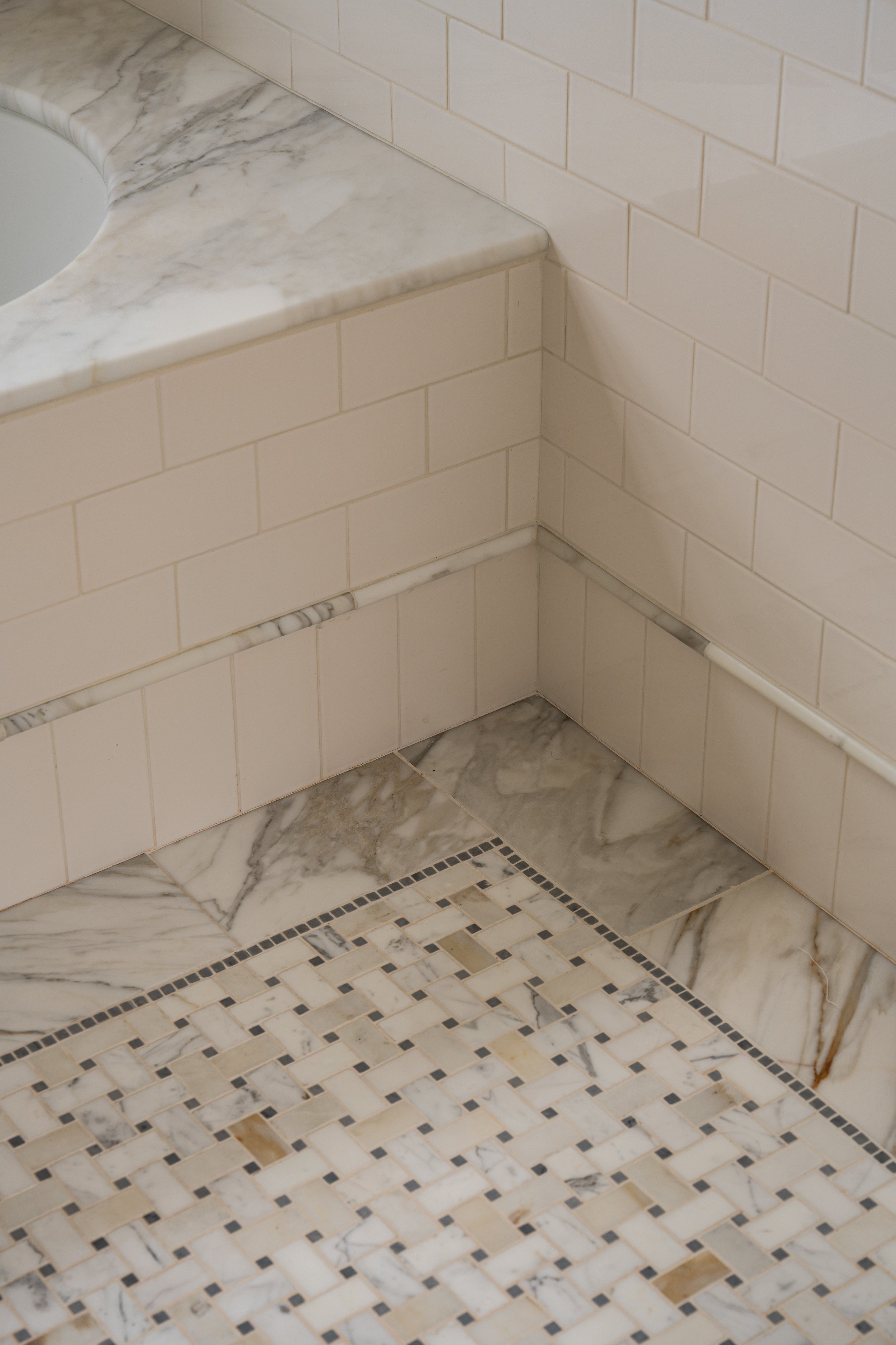 Wet room tub clad in marble with marble tile inset and border meets creamy classic subway tile.