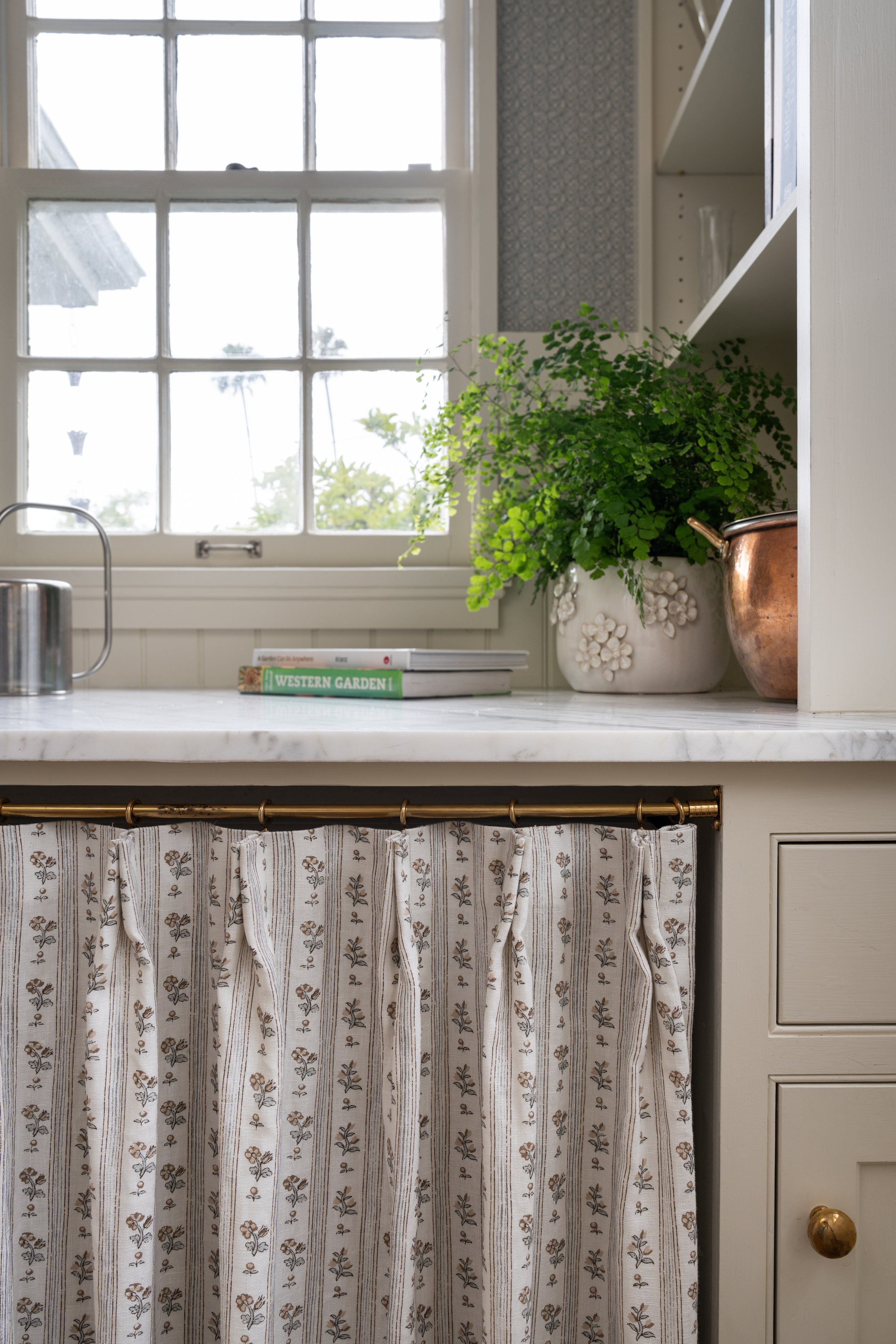 Laundry room detail of garden area and pinch pleat curtain hiding machines.