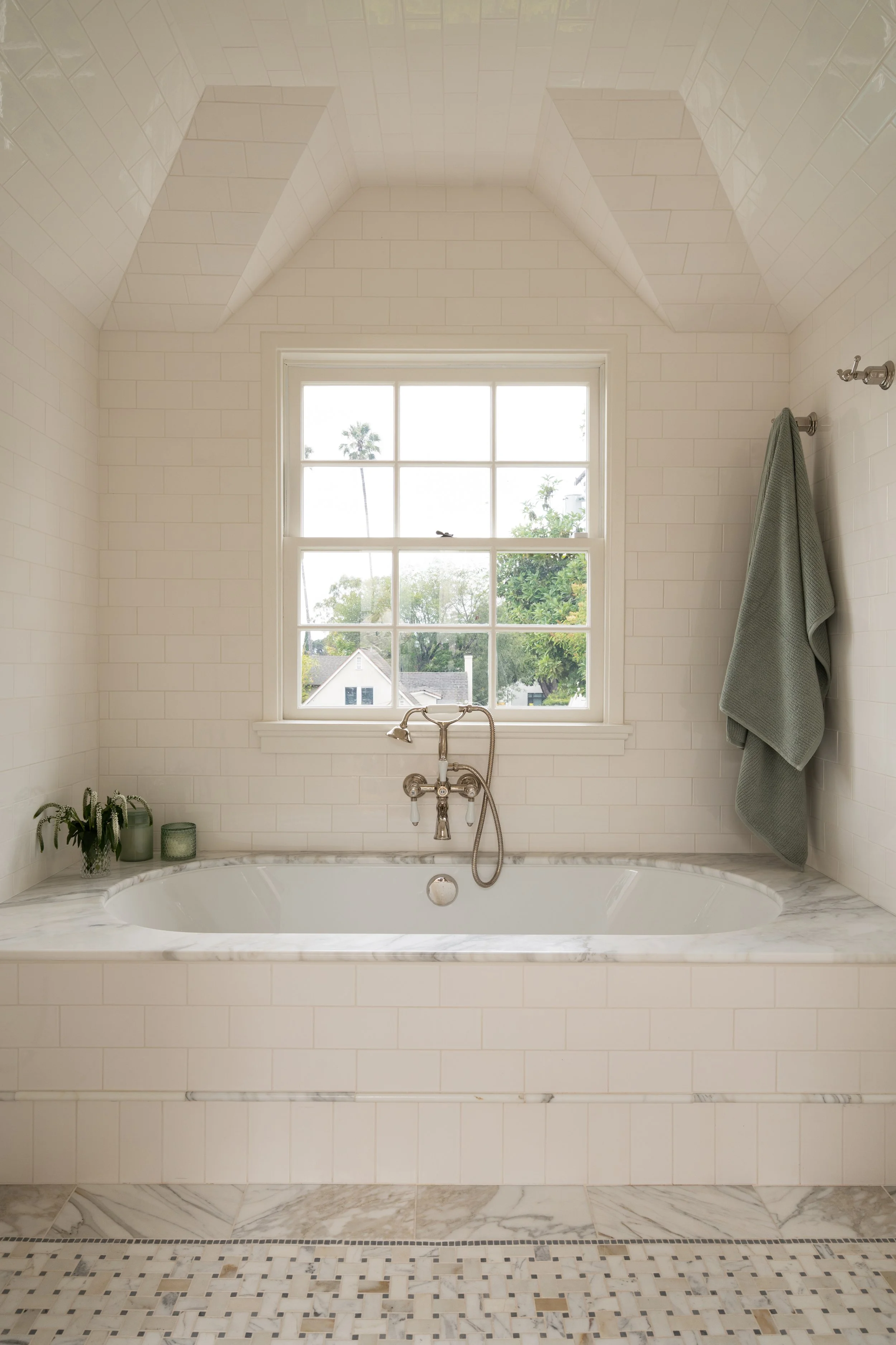 Cream subway tile wetroom with built in oval tub, marble deck and marble floor, polished nicel faucet and spa feel.