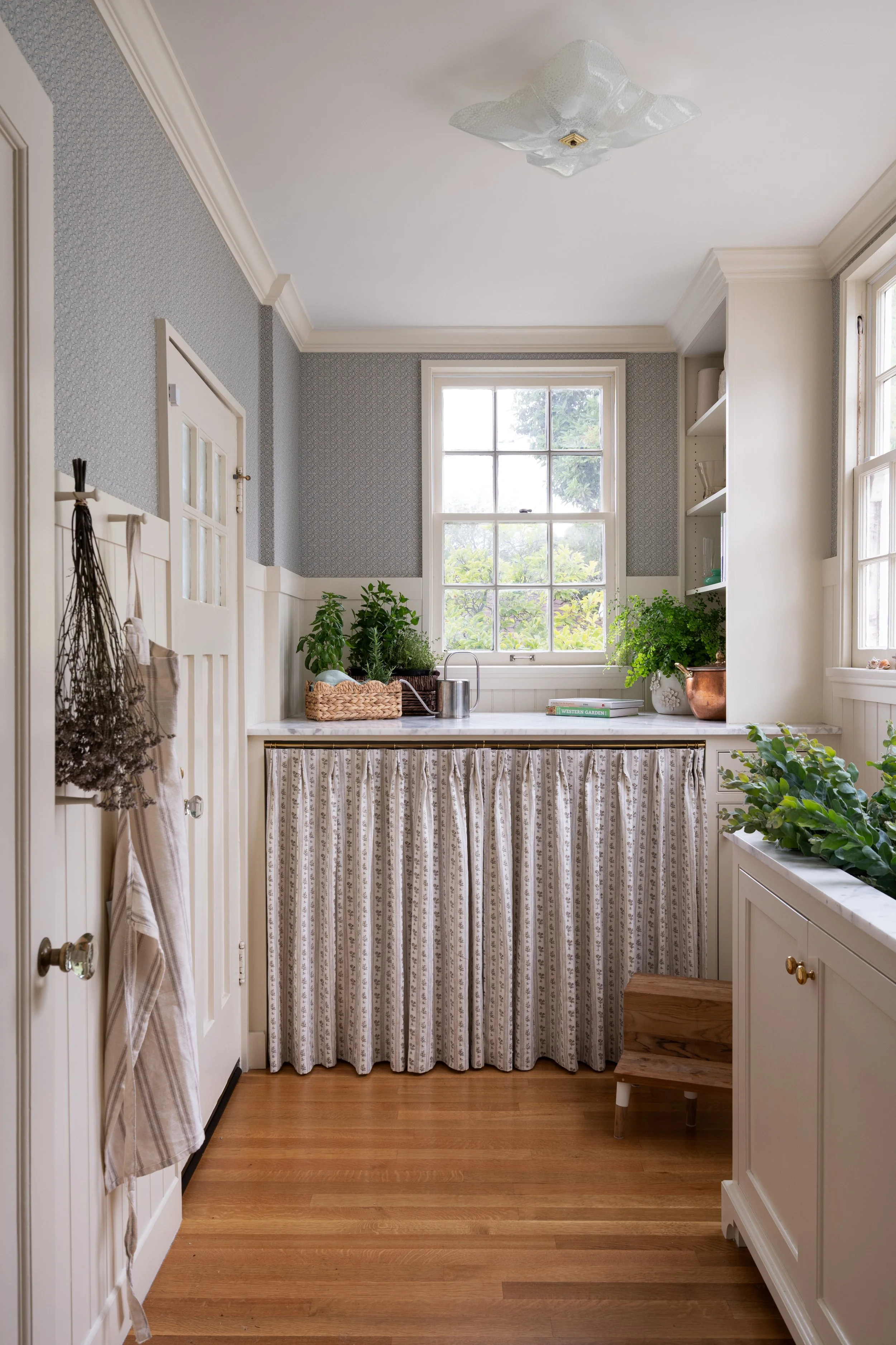 English-inspired laundry room featuring period detailing, wallpaper, and a curtain to hide the machines.