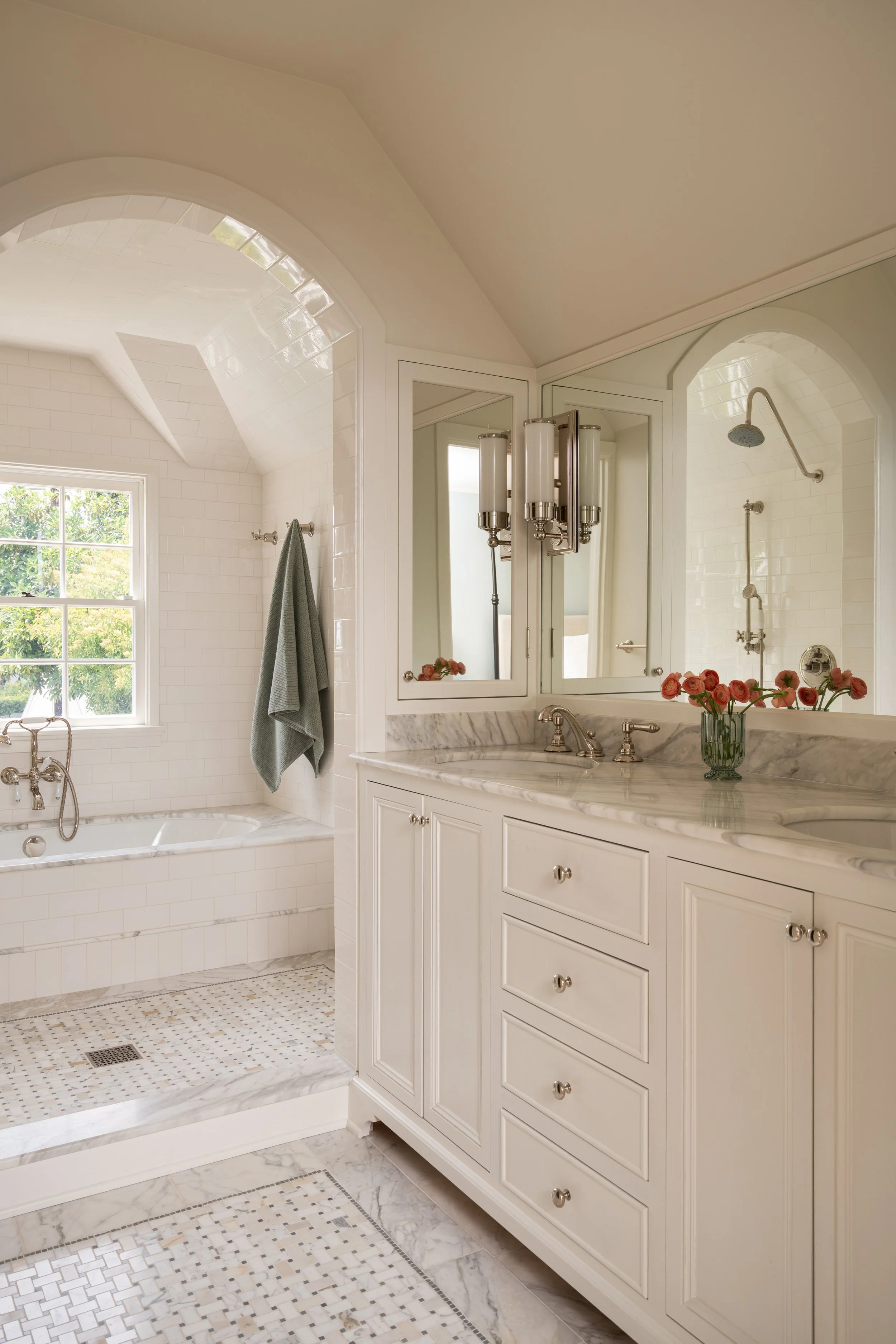 Arched opening into tile and marble wetroom with custom millwork and polished nickel fixtures.