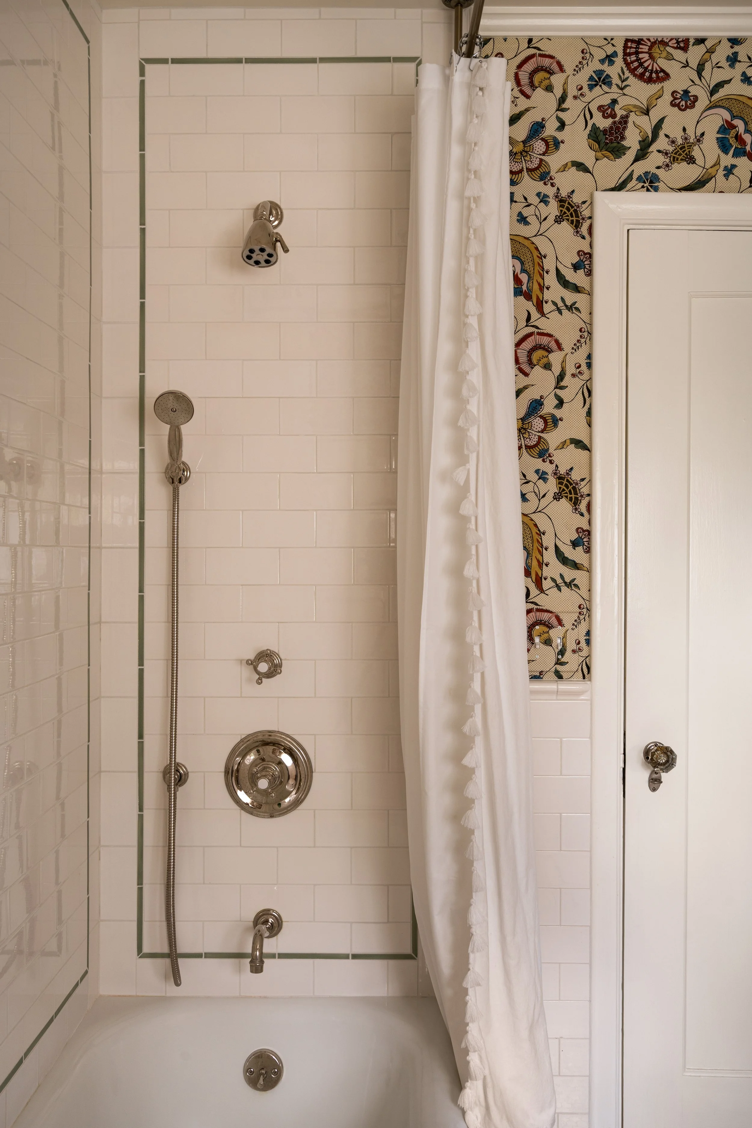 Decorative tile accent and fun shower curtain play off colorfull wallpaper with polished nickel plumbing fixtures.