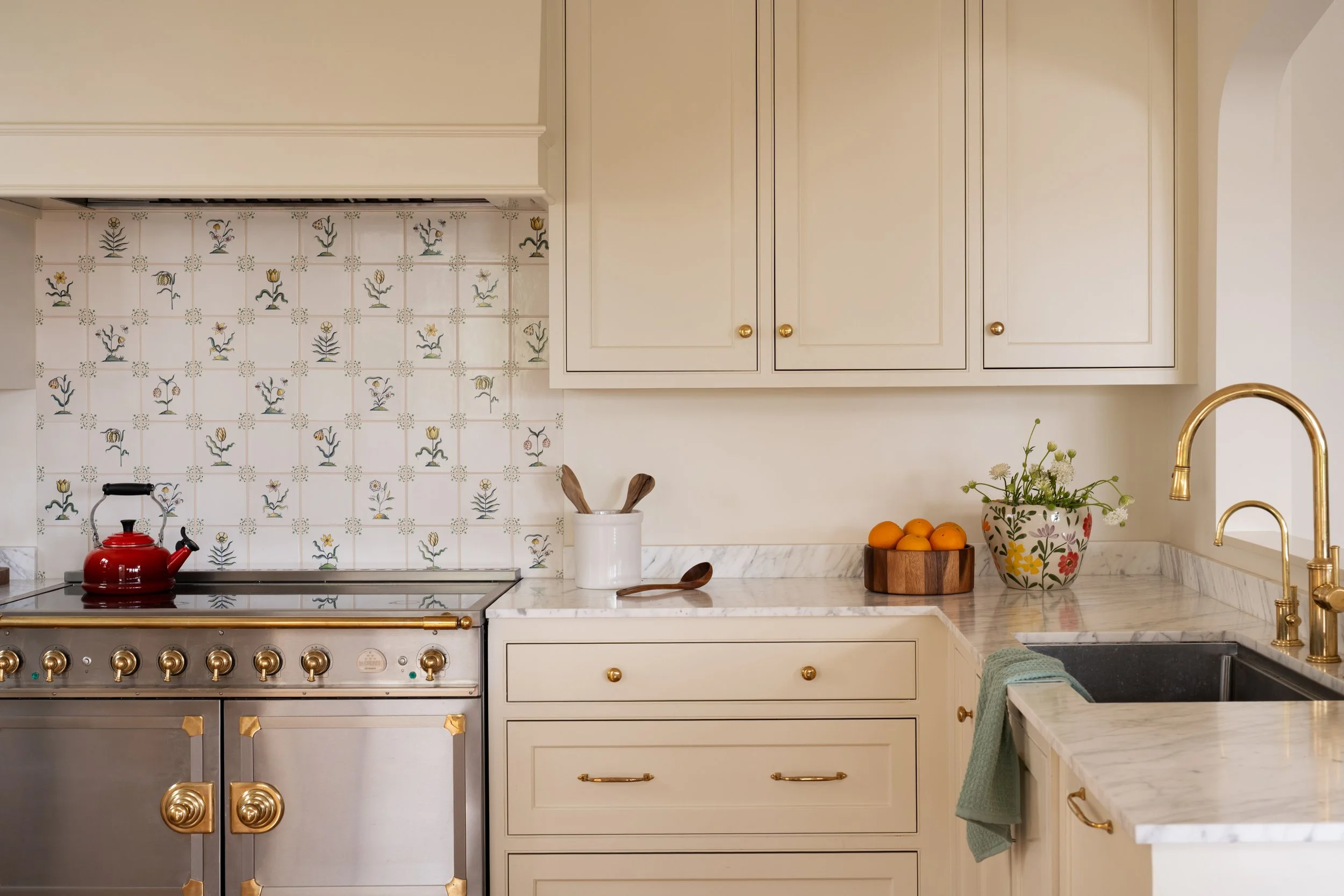 Kitchen detail feature a La Cornue range and hand-painted tile backsplash with brass accents.