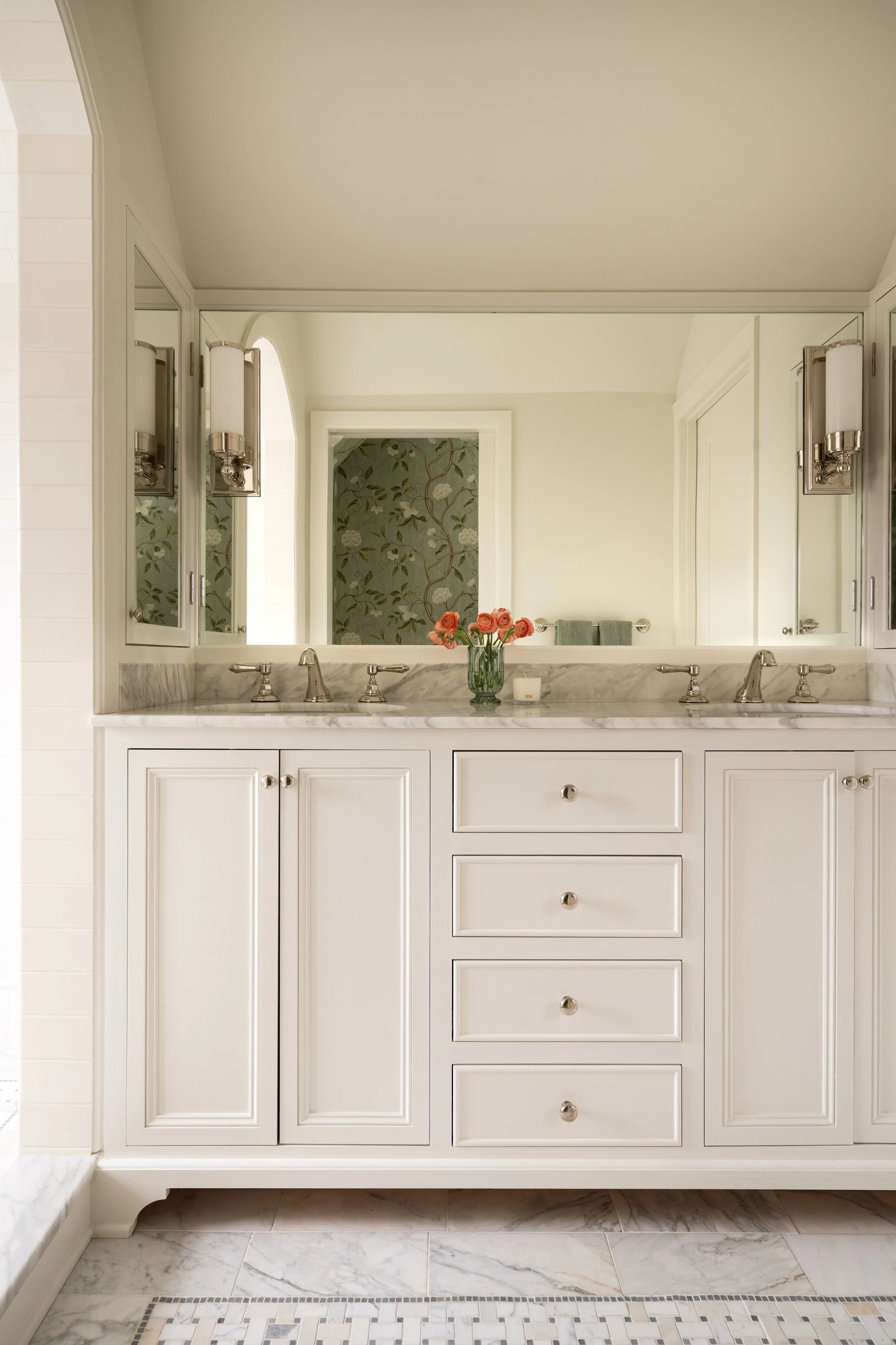 Decorative marble inset floor and custom inset vanity with floral wallpaper.