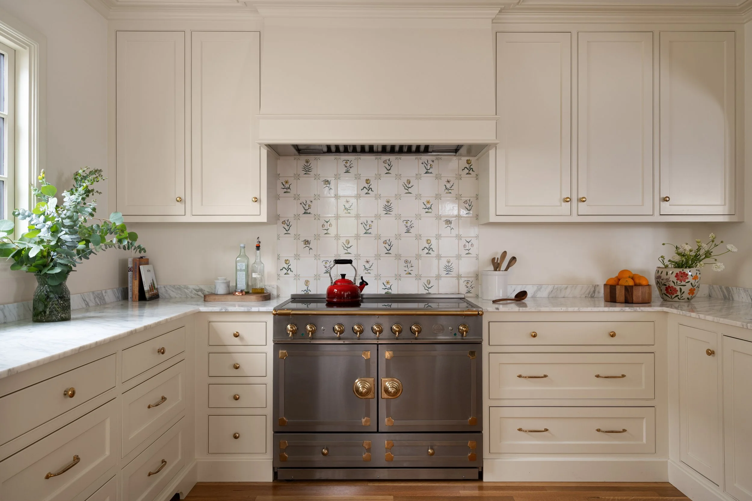 Marble counters with creamy inset cabinet details provide english cottage feel.