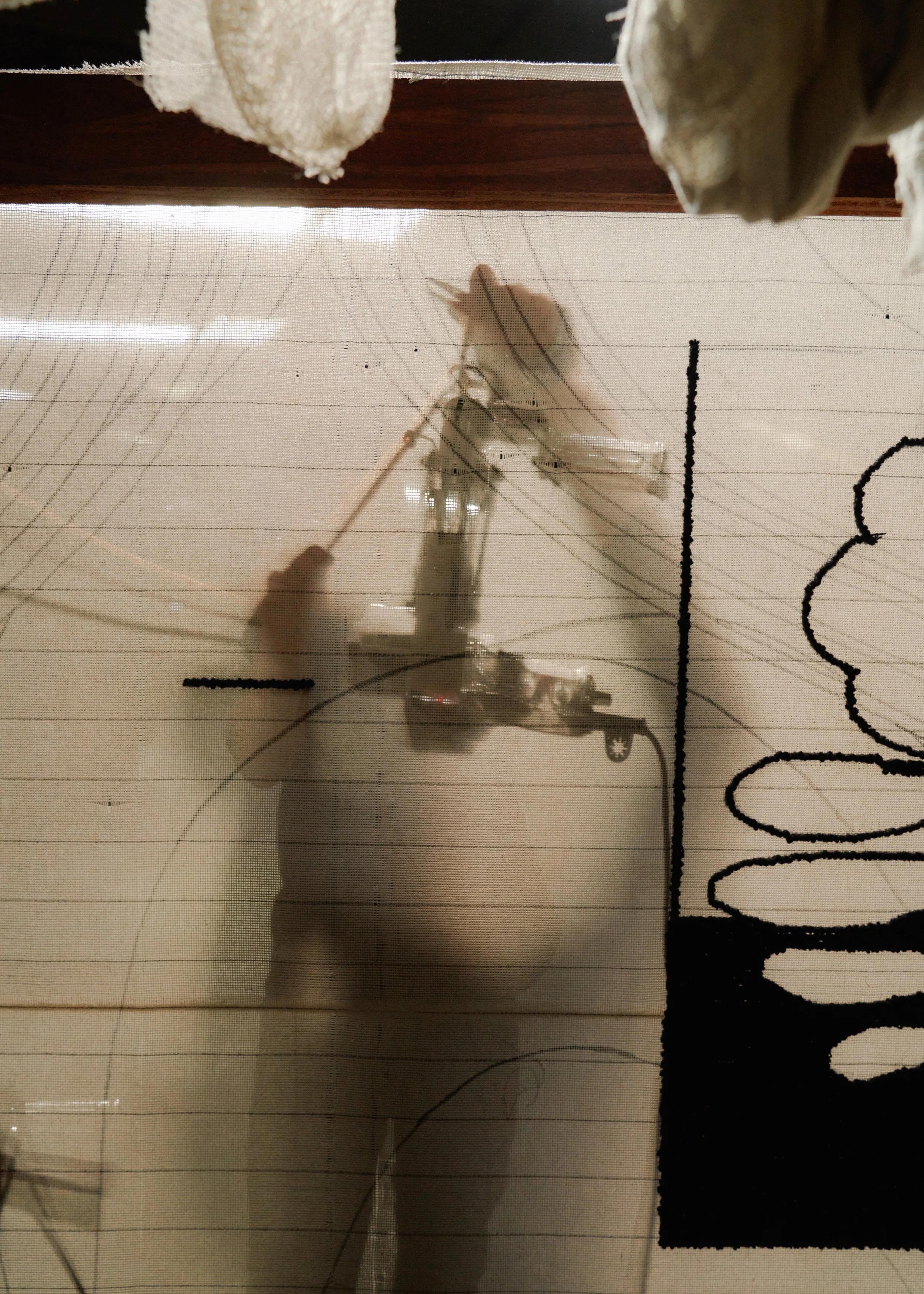 A shadow of a person using a hand tufting gun