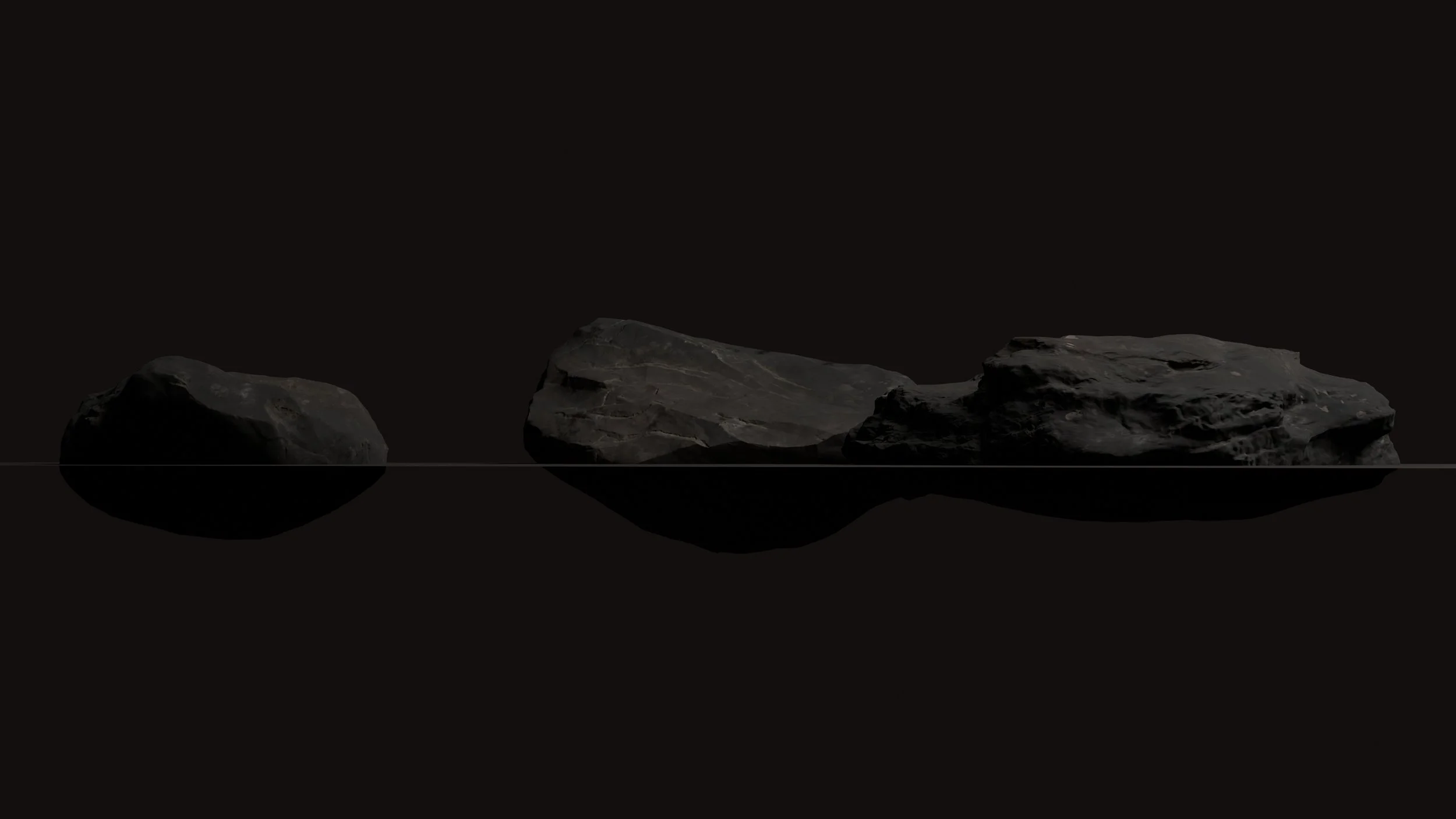Three dark rocks are lined up horizontally against a black background with a faint reflection underneath.