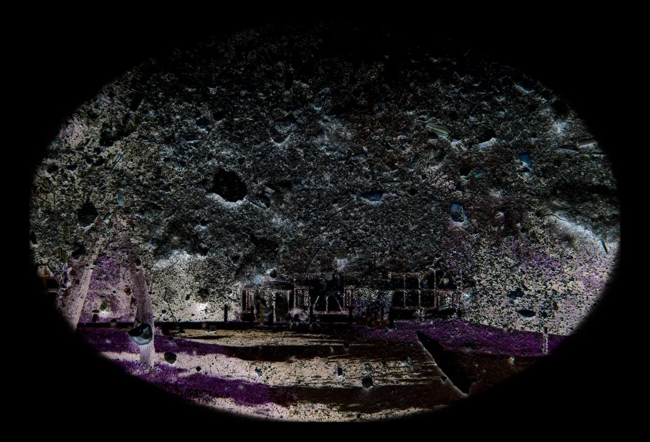 View of a park with trees and a playground, seen through a circular peephole, with black edges around the oval shape.
