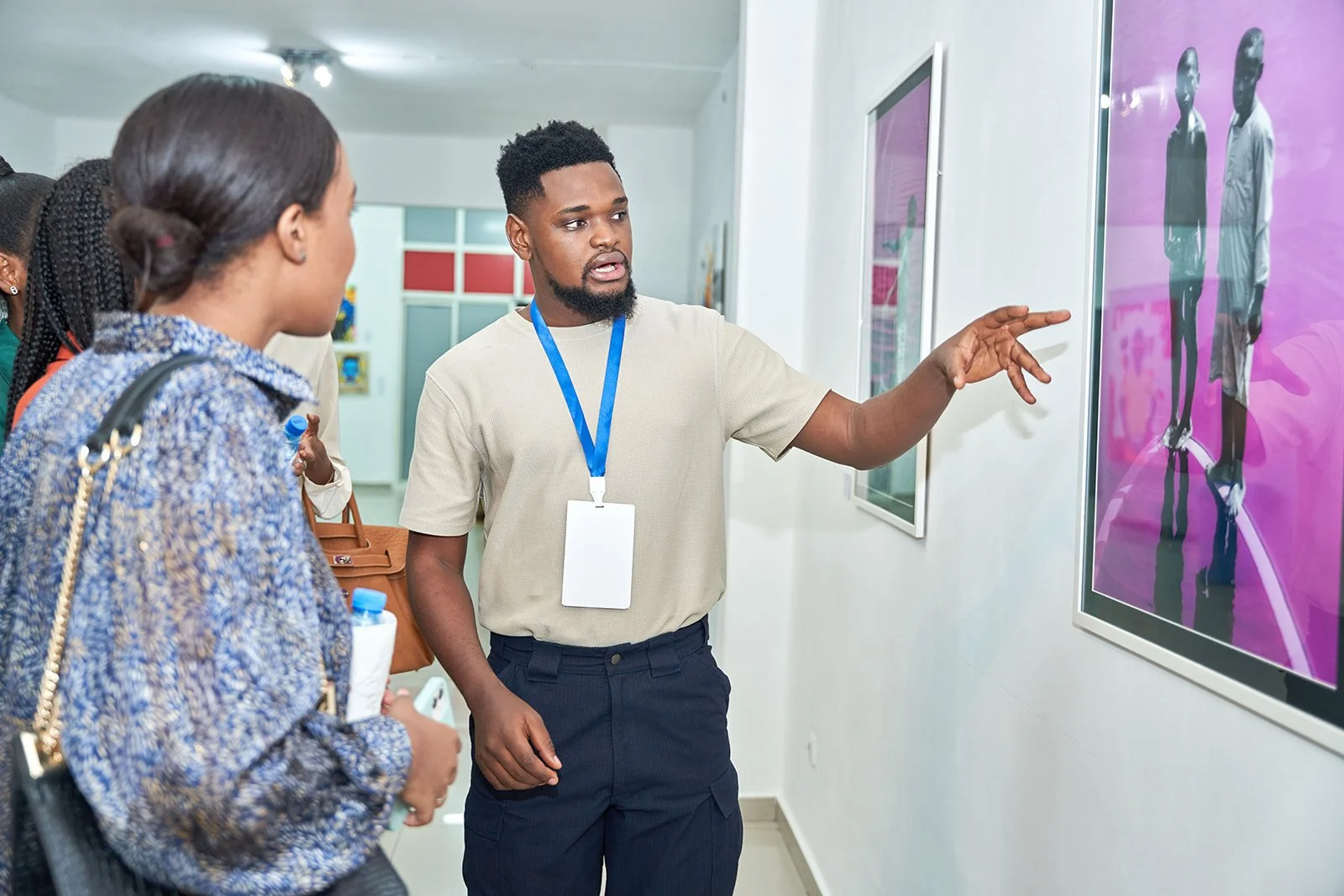 Kreative Kwame pointing at a pink photo and explaining to three women