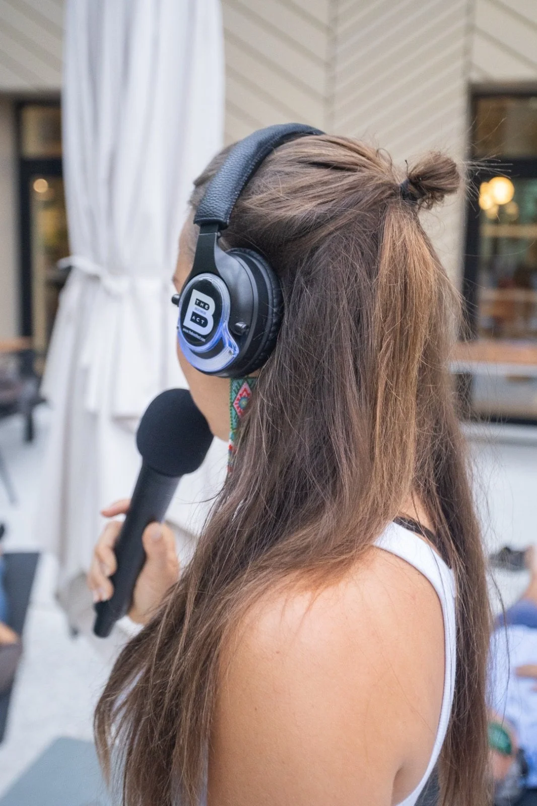 Modern wooden building with large window, situated in a mountainous landscape with dry grass and sparse trees.