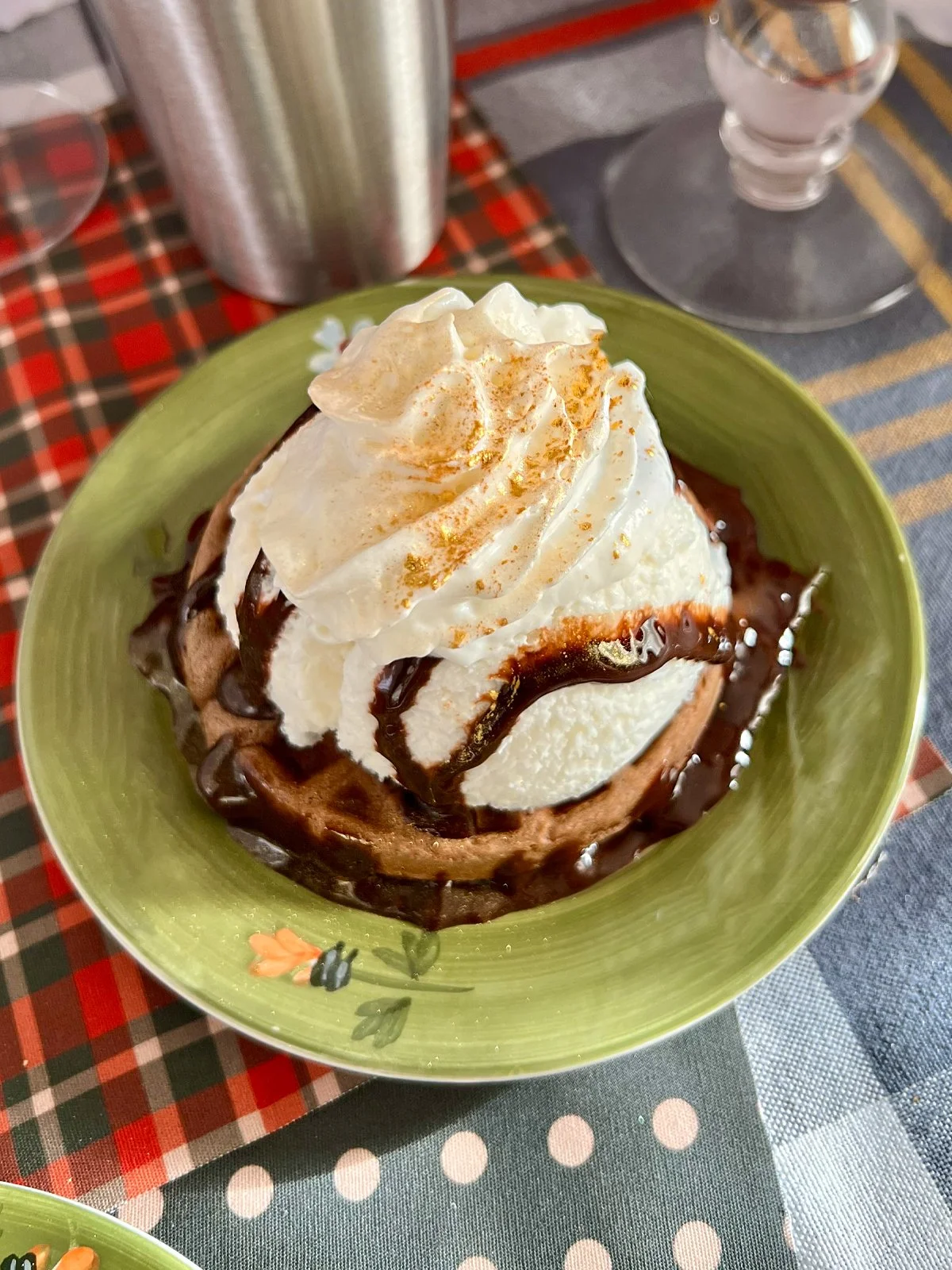 A mini hot cocoa waffle dessert topped with vanilla ice cream, whipped cream, and chocolate syrup, finished with edible gold for a festive New Year’s Eve treat with retro flair.