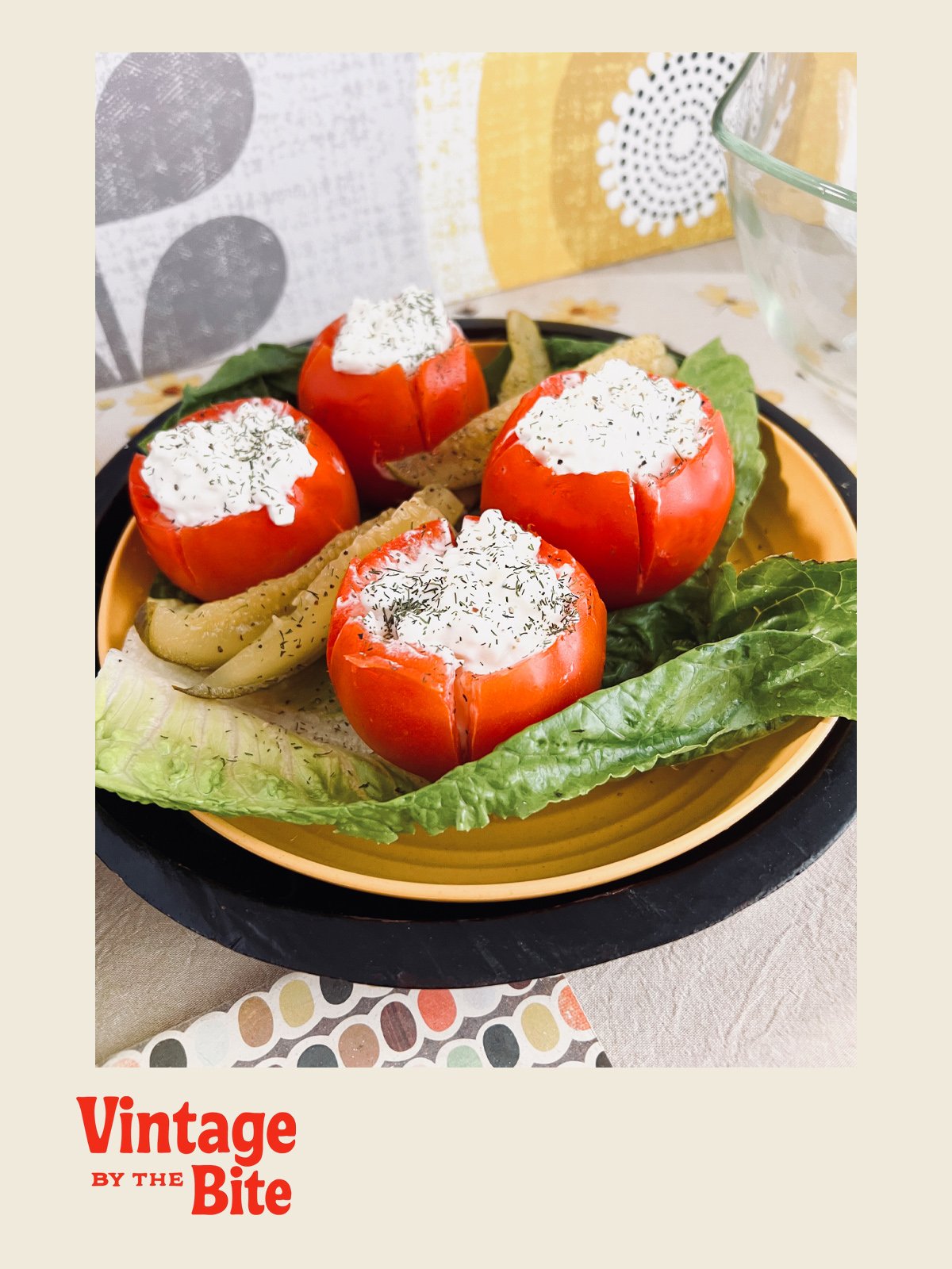 Retro-style photo of stuffed tomatoes with herbed cottage cheese on romaine lettuce, served on a yellow plate with 1970s-inspired table decor.