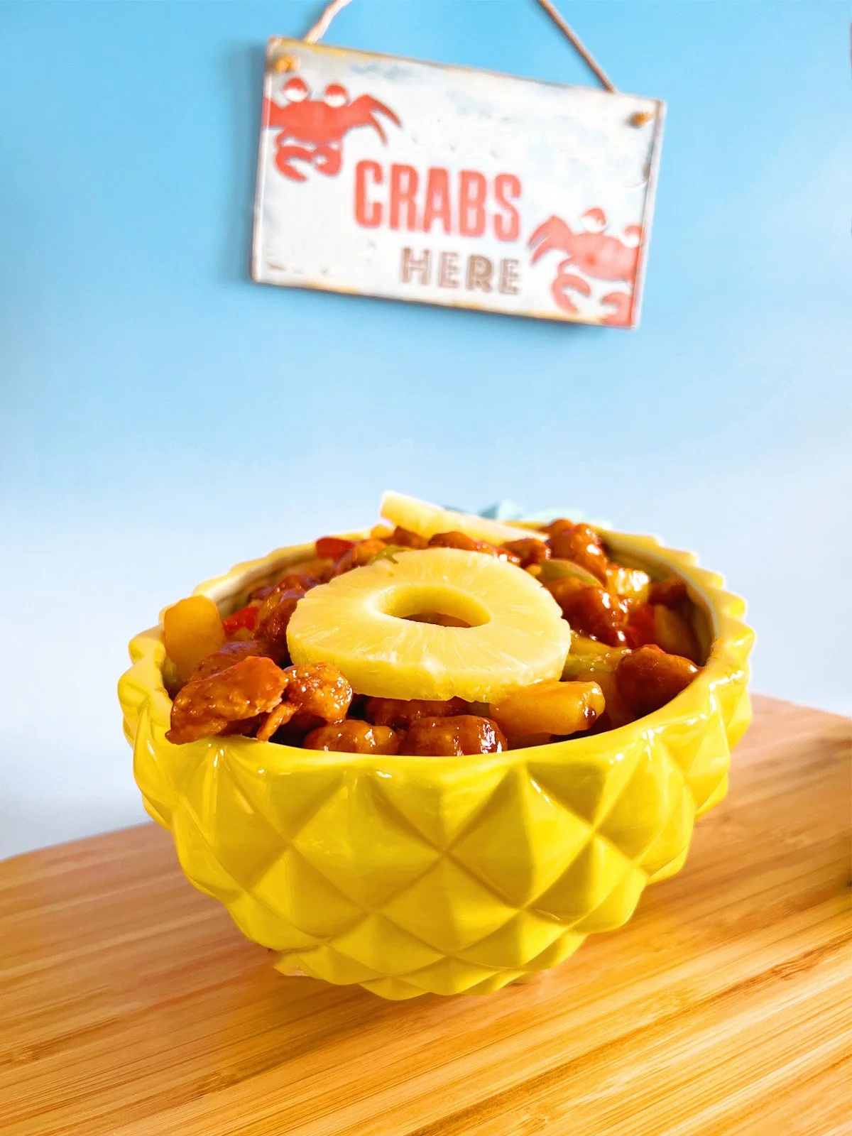 1970s-style sweet and sour chicken in a yellow pineapple bowl, topped with pineapple rings and colorful peppers, inspired by a vintage Don the Beachcomber recipe.
