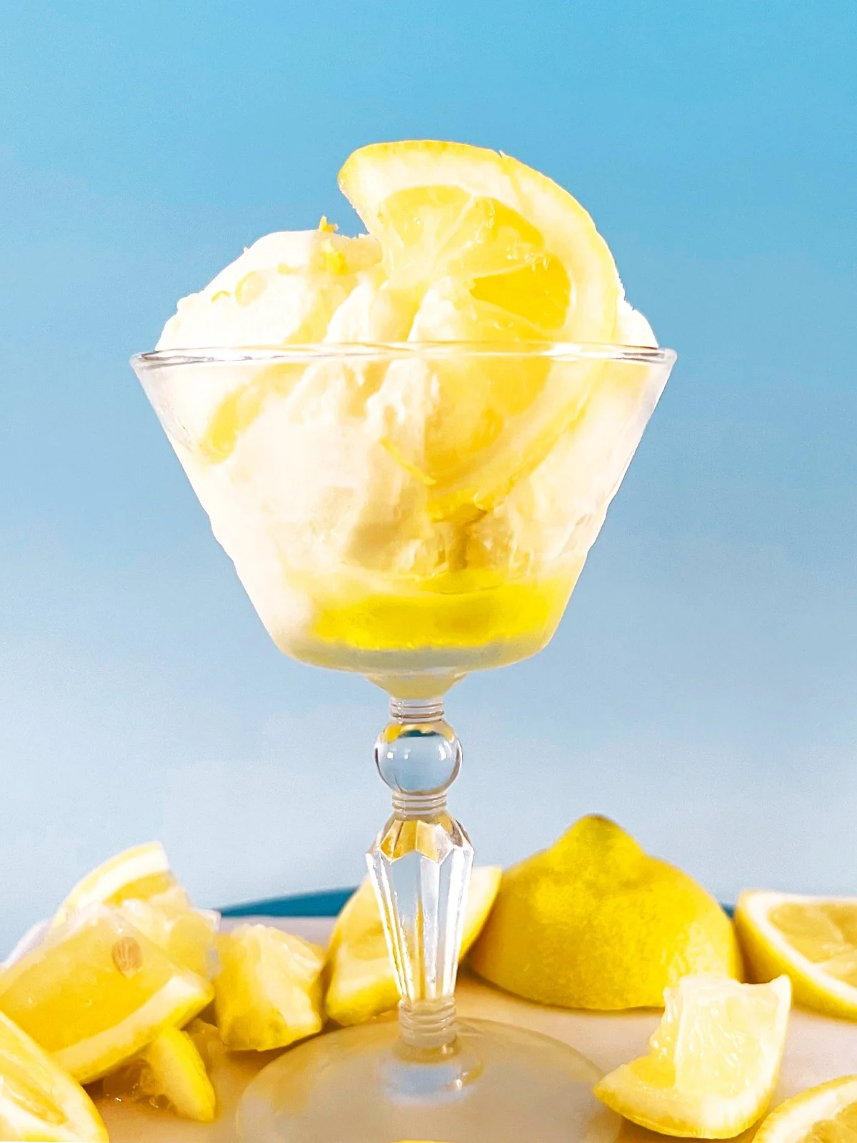 yellow lemon syrup, styled on a tray with fresh lemon slices against a soft blue background.