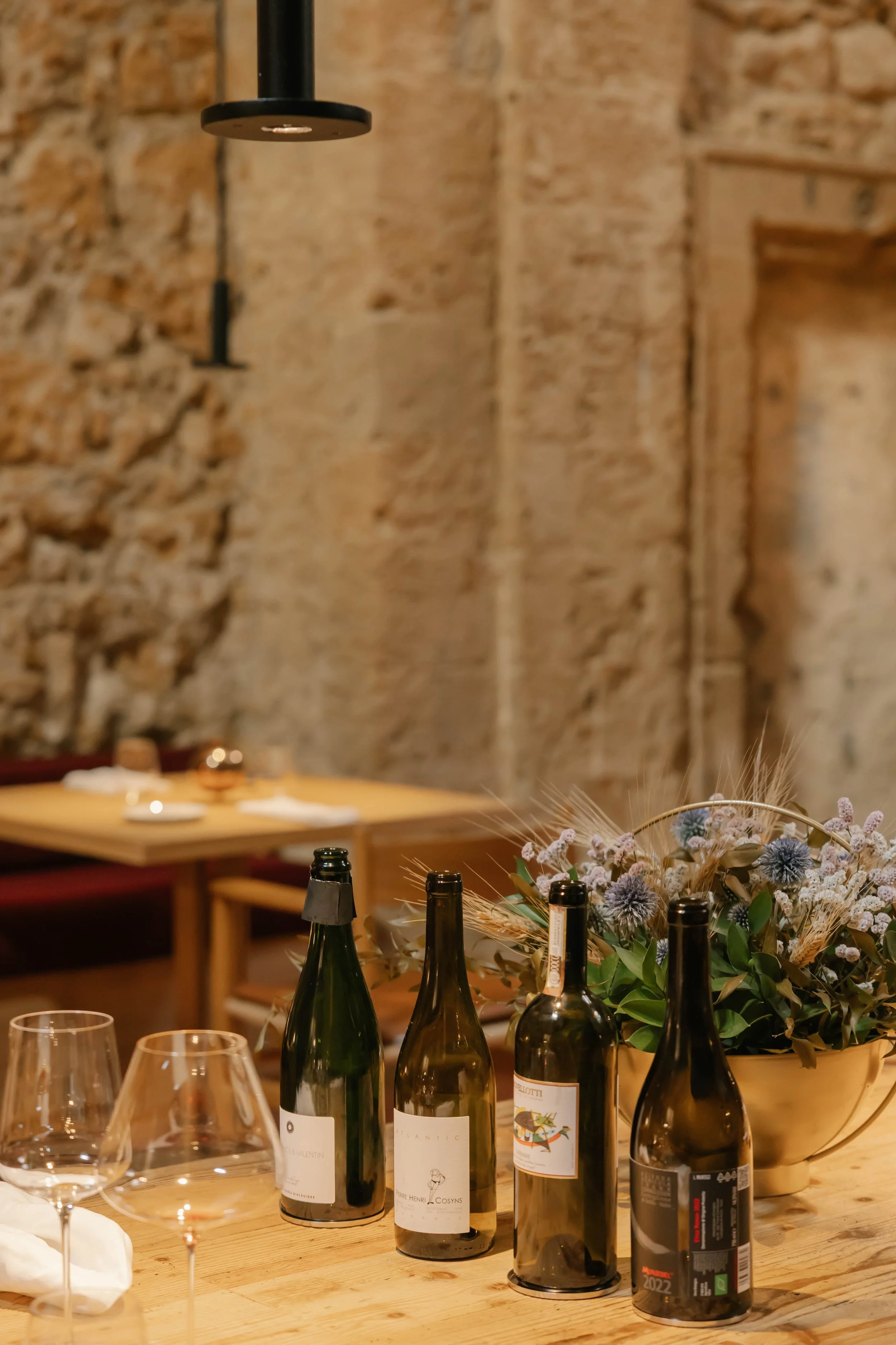 A table laid with open bottles in a stone dining room