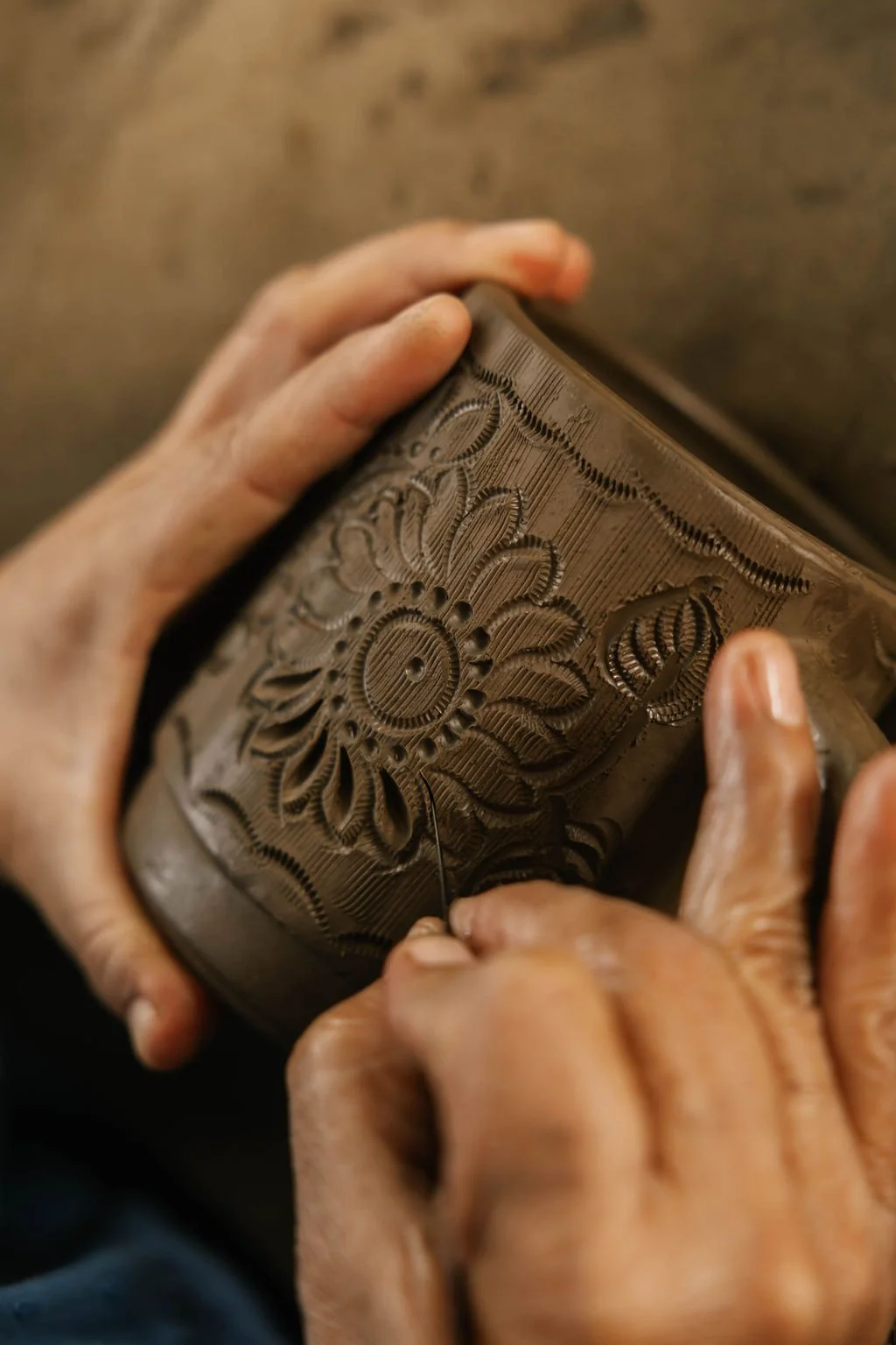 Black Clay Pottery Experience in Oaxaca. Close-up of a person carving intricate floral patterns into clay with a fine tool, focusing on the detailed craftsmanship.