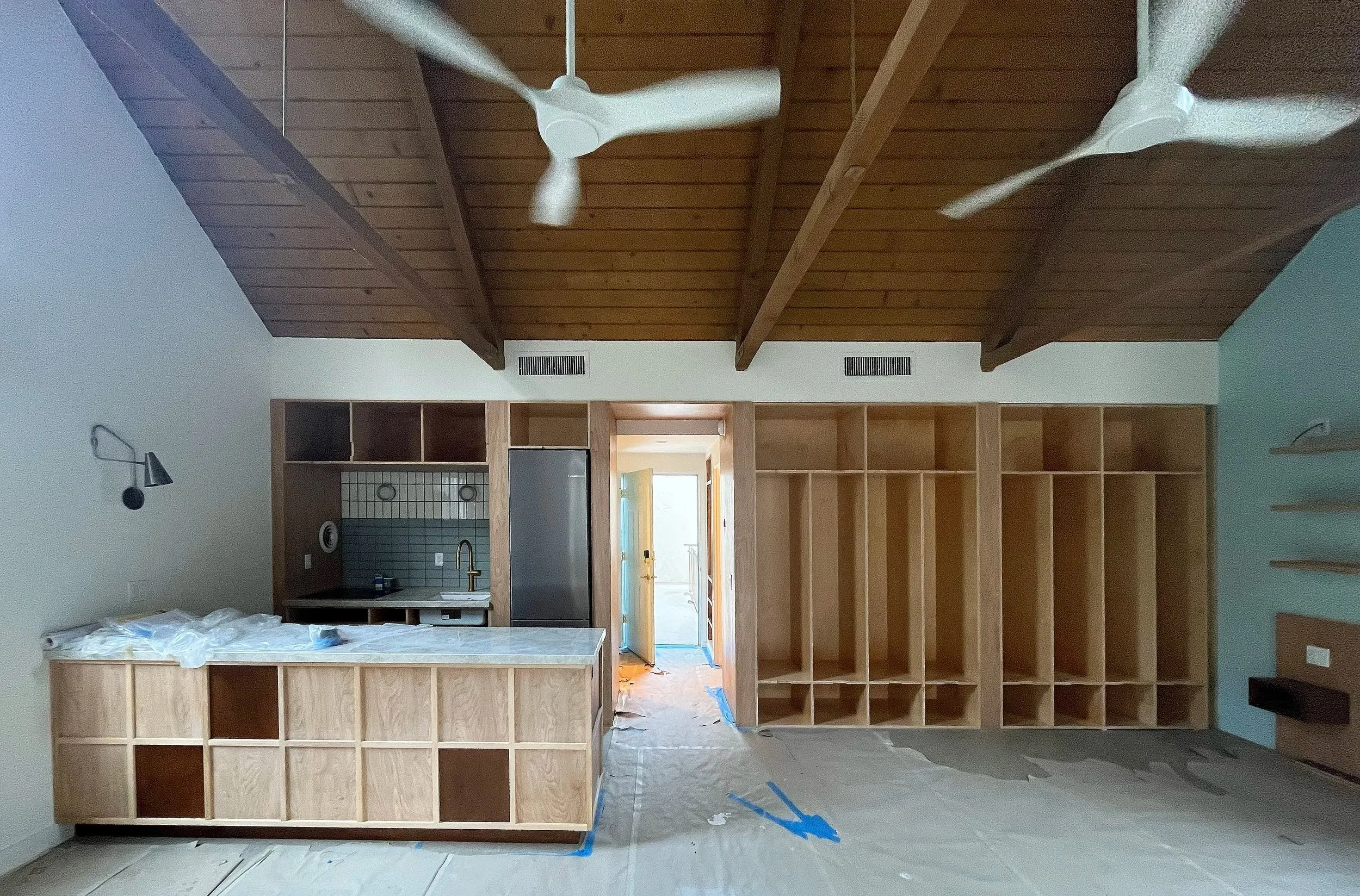 modern upscale kitchen and bedroom interior design for boutique hospitality featuring custom wood kitchen cabinetry and built-in bedroom closet system with dark brown stained accents