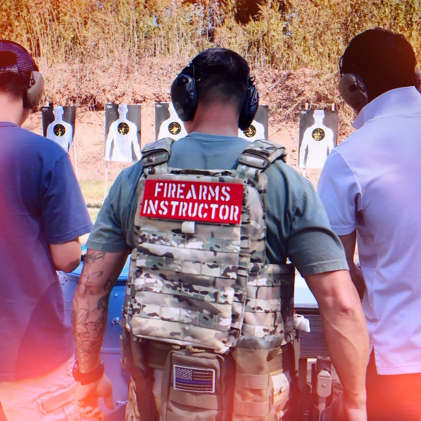 Target with a cluster of bullet holes near the center and a black handgun with a tactical light and red dot sight placed on it.