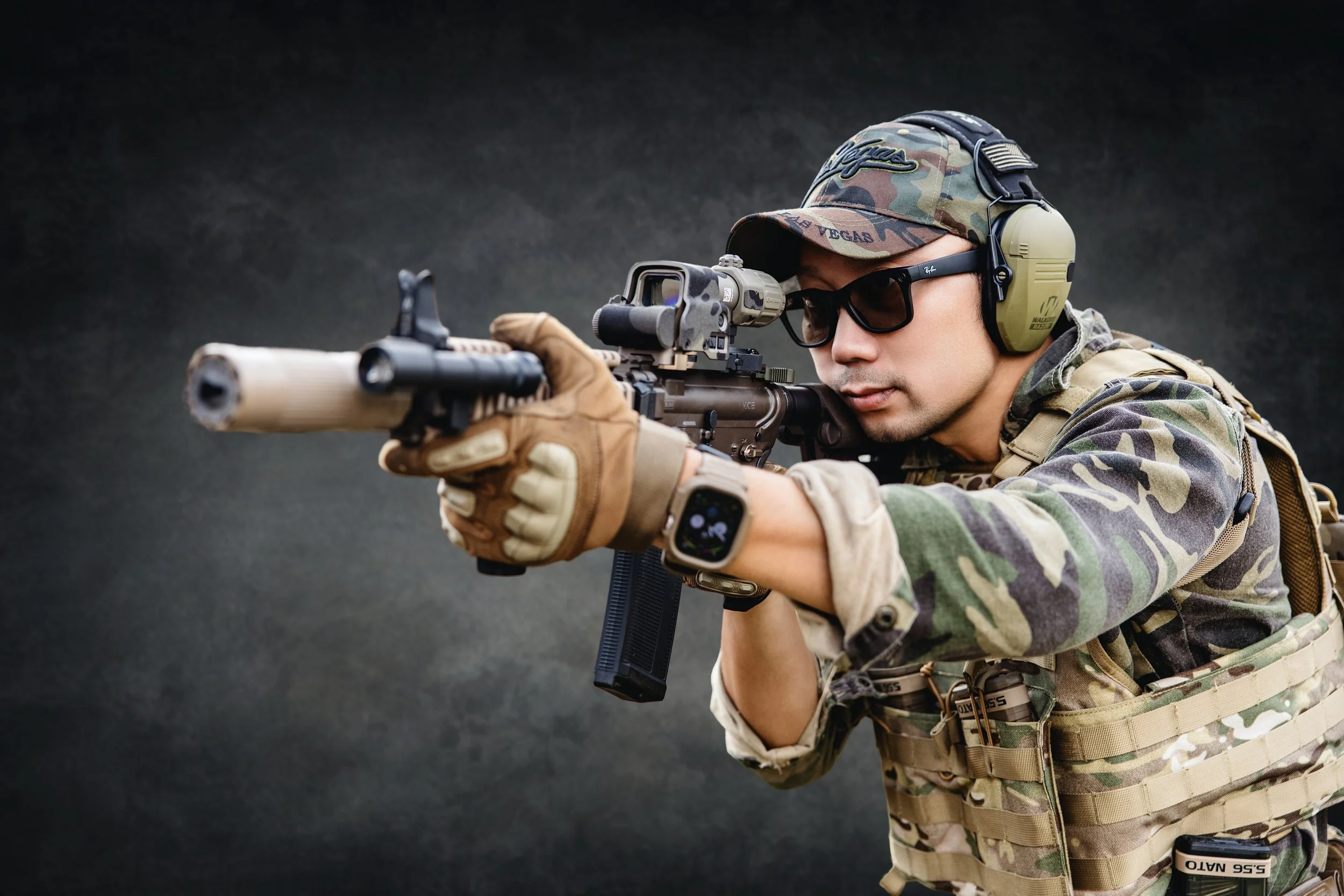Person with glasses and a green shirt sitting in a modern living room, surrounded by camera equipment, with a large window showing a snowy landscape outside.