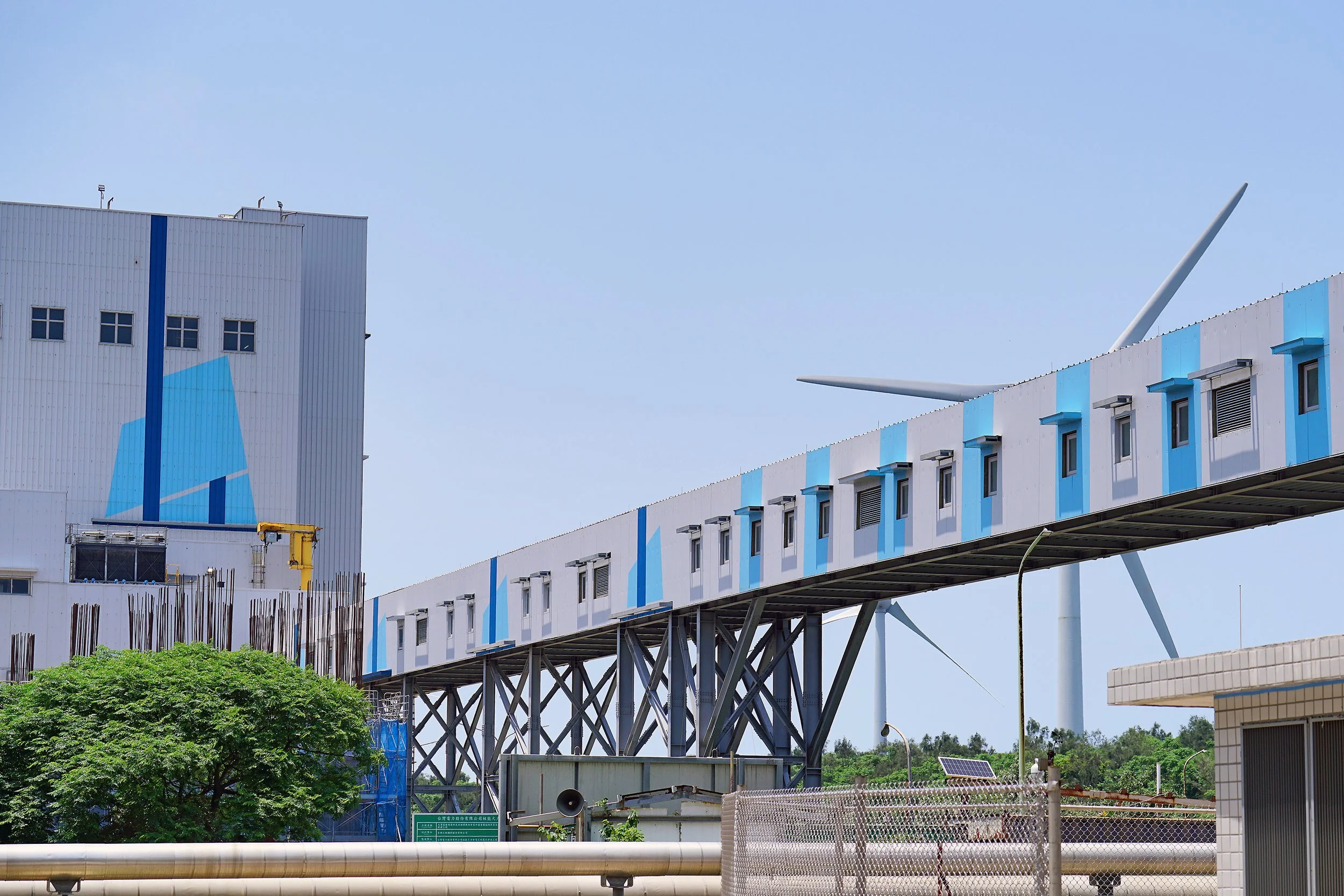 大潭電廠輸送廊道金屬外牆，後方為濱海風力發電機組
