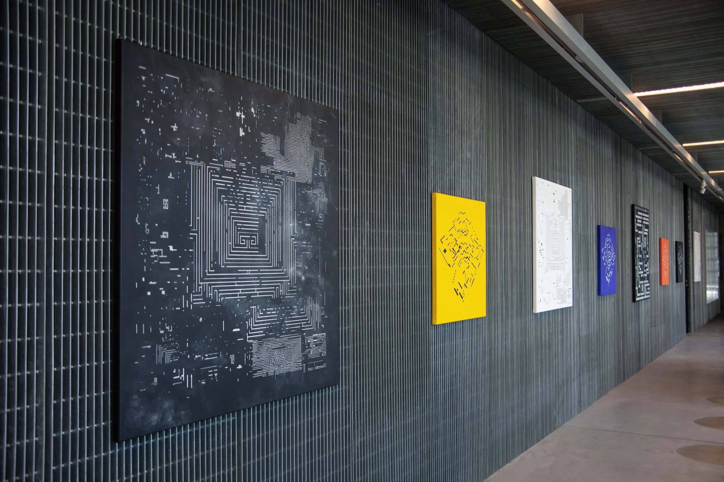 Pared con pinturas abstractas de diferentes colores, en un pasillo moderno.