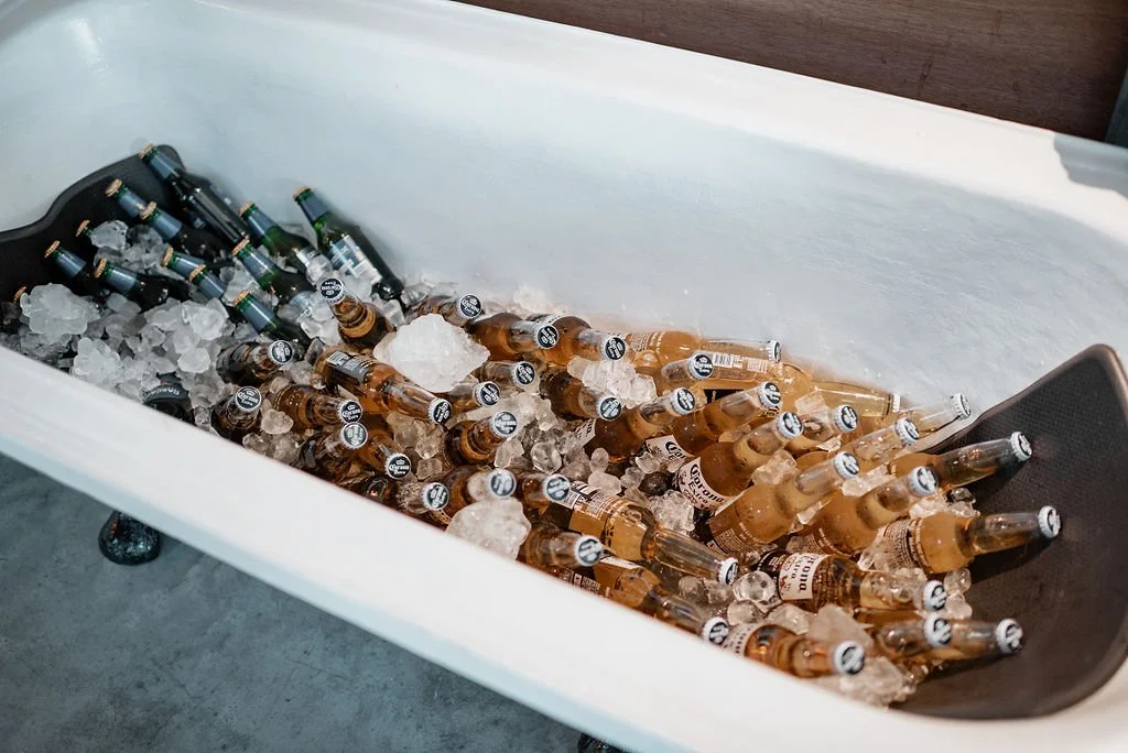 A white bathtub filled with ice and numerous bottles of beer.
