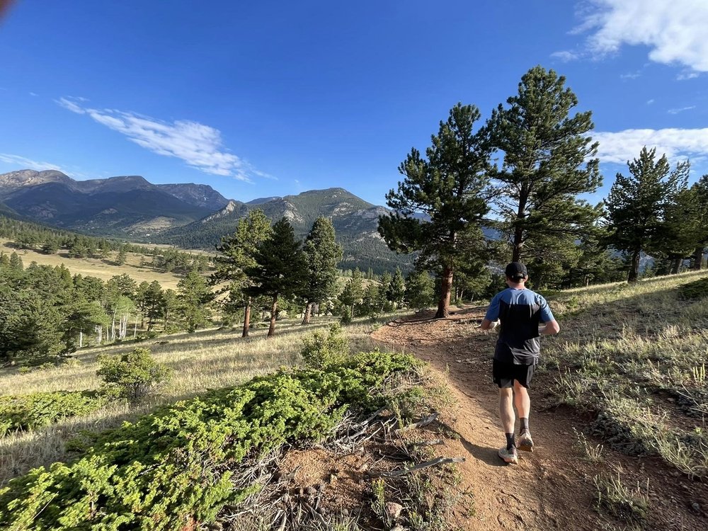 A runner on a singletrack trail with mountains behind