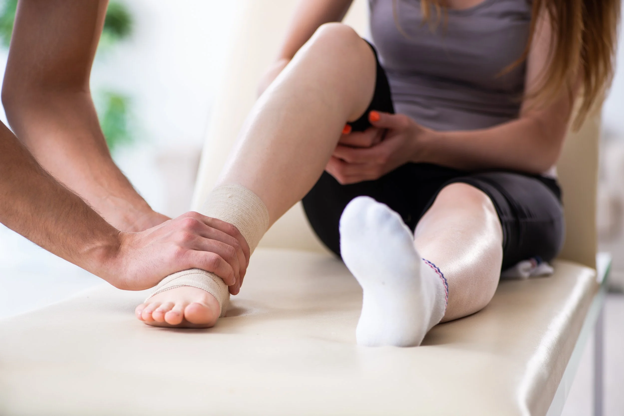 Person receiving medical treatment or injury care on their leg from a healthcare professional in a clinical setting.