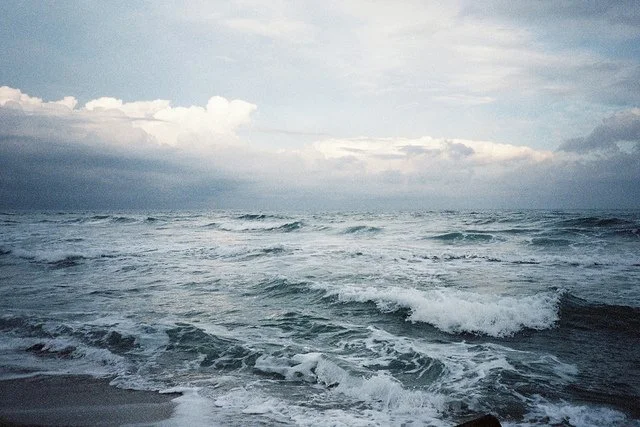 Ocean waves crashing on the shore under cloudy sky