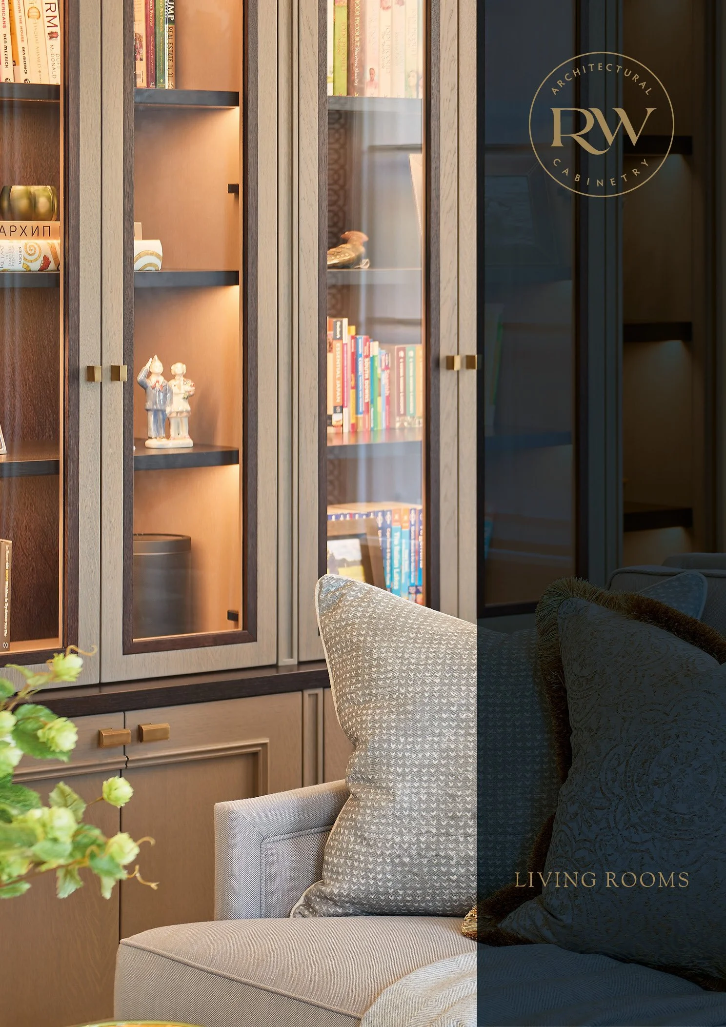 A living room with a wooden bookshelf displaying books and decorative items, a light-colored armchair with a patterned cushion, and a dark-colored pillow, with a partial view of the room's interior.