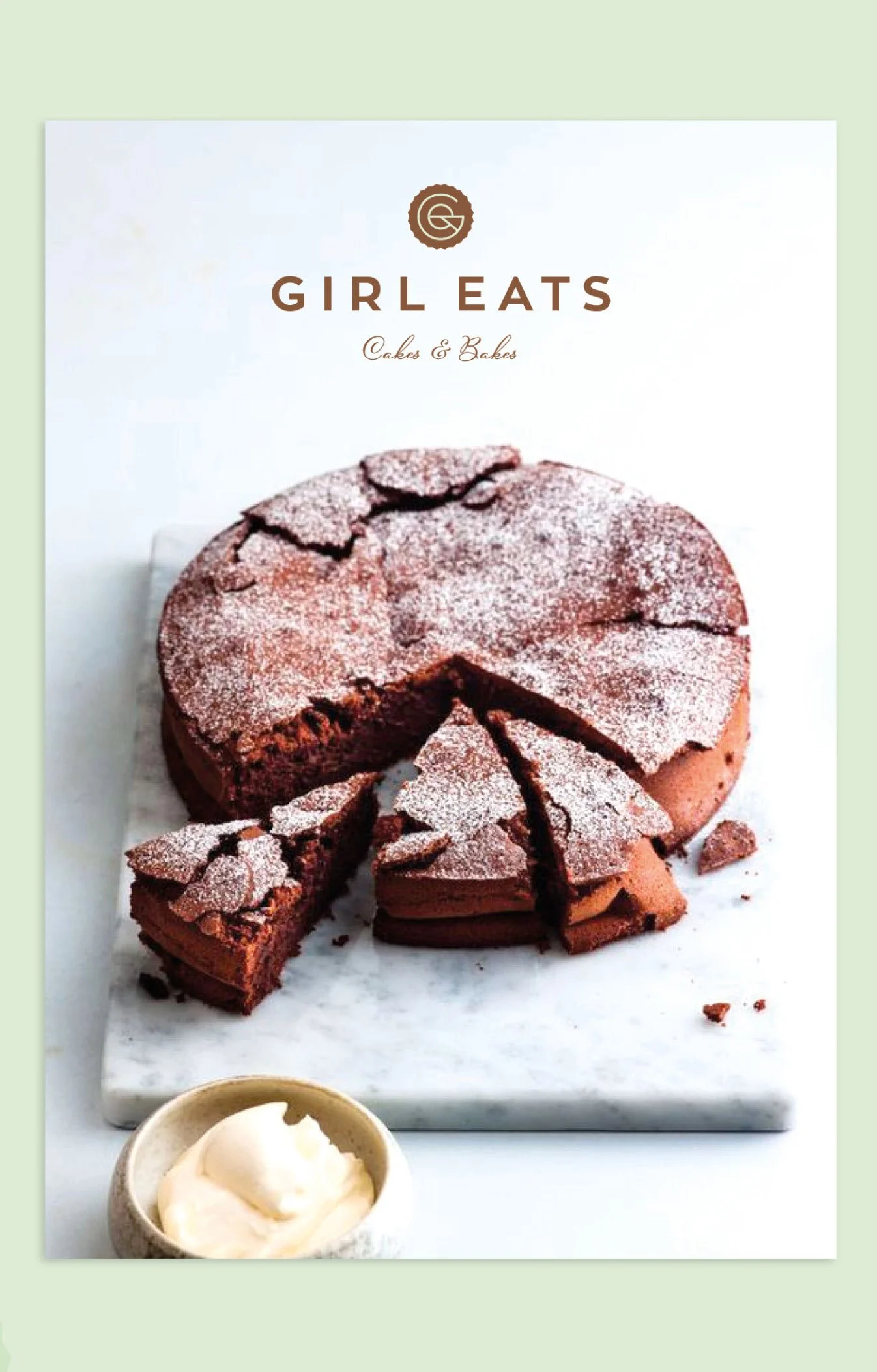 A cookbook cover titled 'Girl Eats Cakes & Bakes' featuring a chocolate cake dusted with powdered sugar, with a slice removed, on a white marble board, and a small bowl of vanilla ice cream in the foreground.