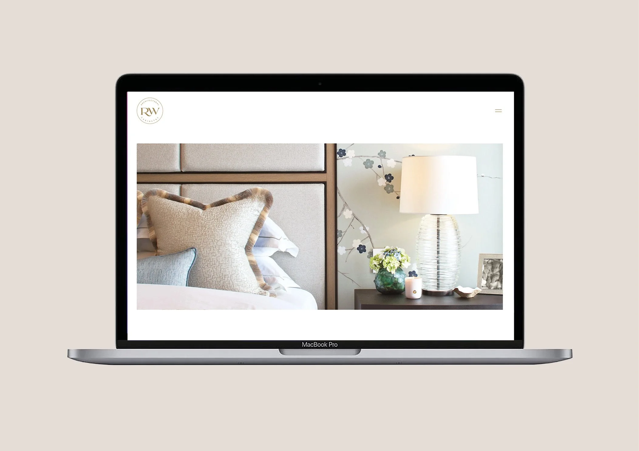 Screenshot of a laptop displaying a home decor website with a bedroom setup, including pillows, a bedside table with a lamp, flower vase, and photo frame.