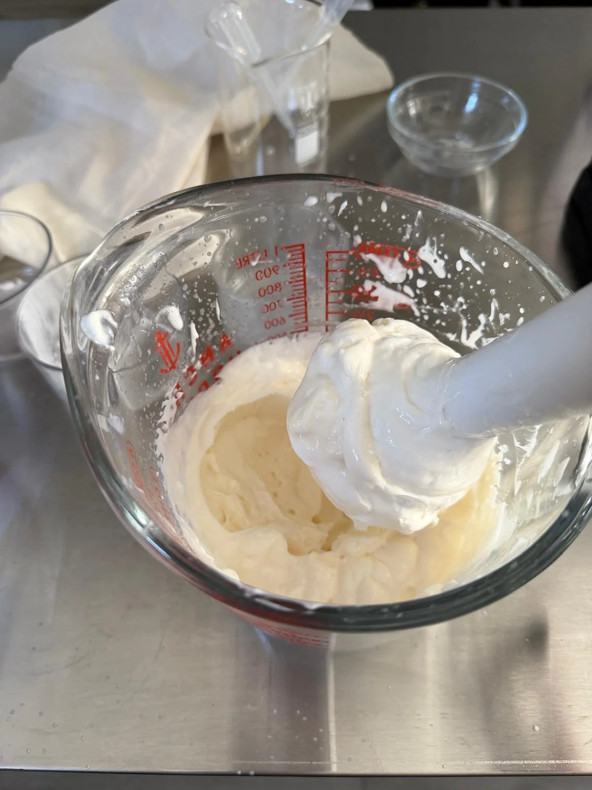 Whipped cream in a glass measuring cup with a spatula