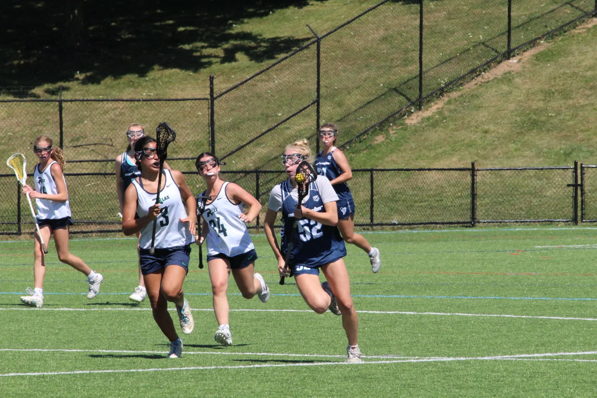 Young women playing lacrosse on a field, with a goal net in the background, Nor'easter Lacrosse, Connecticut's premier lacrosse travel program