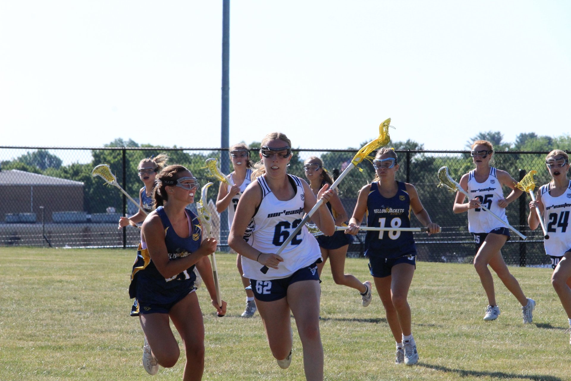 Young women playing lacrosse on a field, with a goal net in the background, Nor'easter Lacrosse, Connecticut's premier lacrosse travel program
