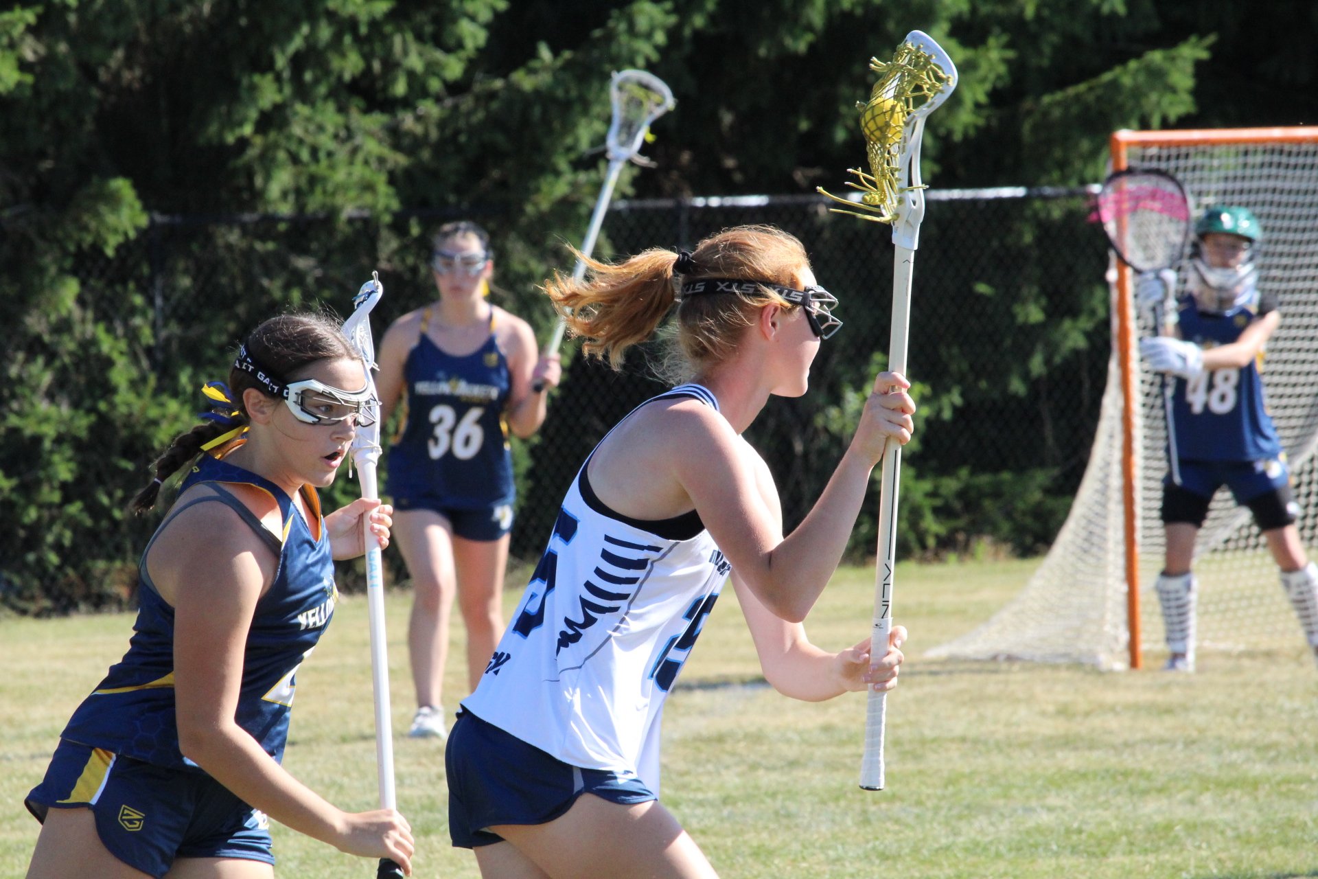 Young women playing lacrosse on a field, with a goal net in the background, Nor'easter Lacrosse, Connecticut's premier lacrosse travel program