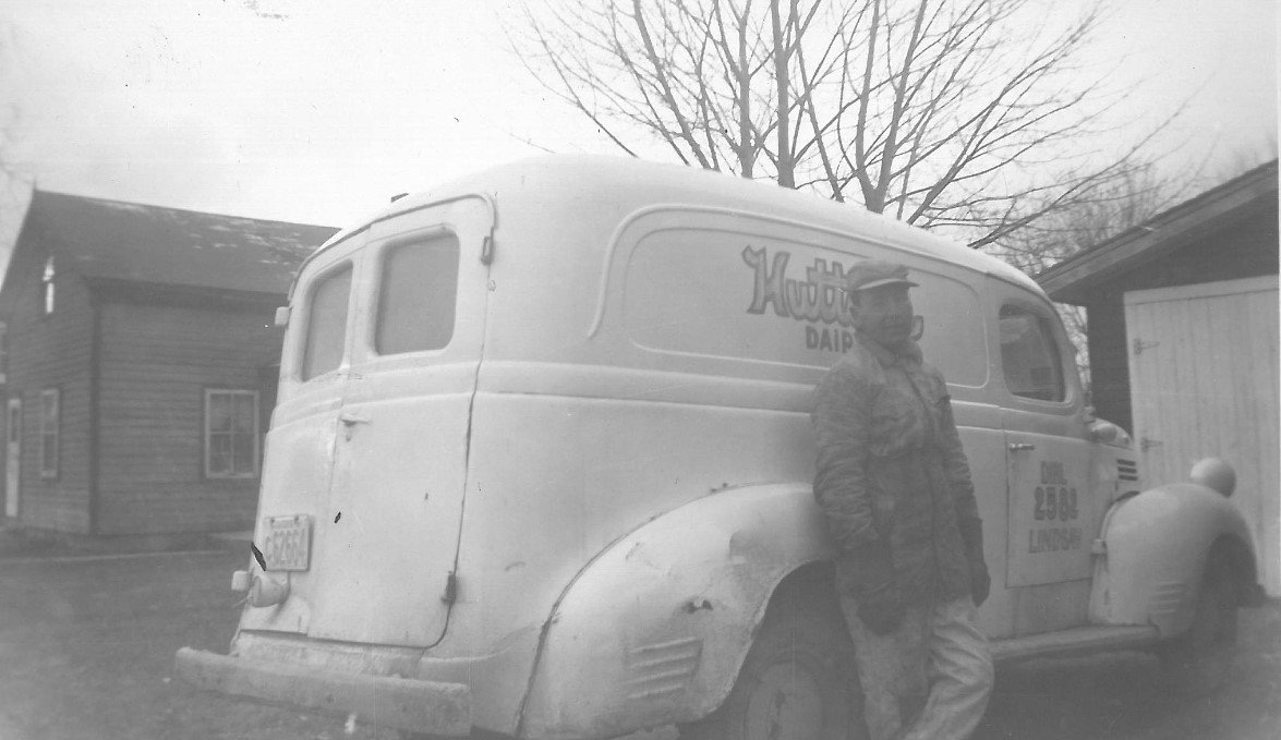  Peter Hutton standing next to a Hutton’s Dairy delivery car. 