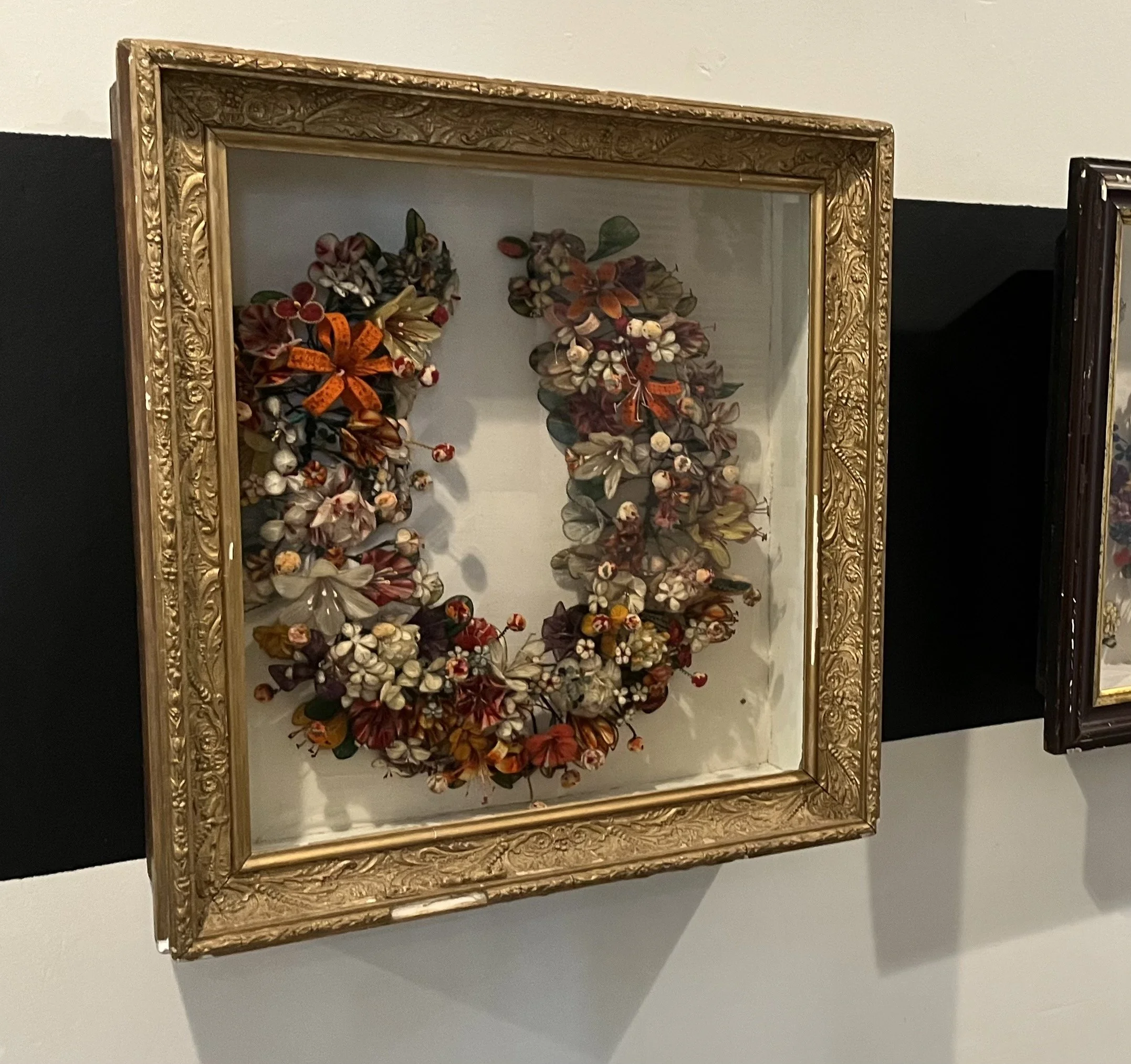 Framed floral artwork with a variety of dried and artificial flowers in a vintage frame.