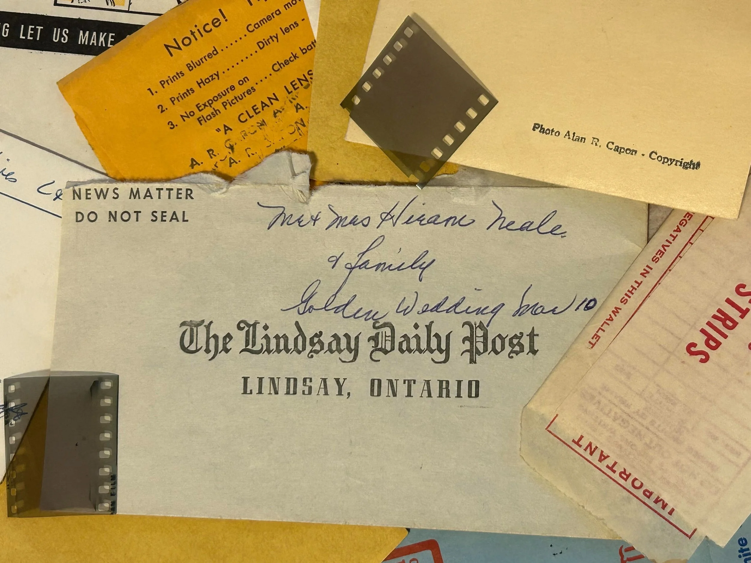Vintage ephemera including a letter from 'The Lindsay Daily Post', small film negatives, and a notice about photography issues. Also features handwriting regarding a golden wedding celebration and copyright note for a photo.