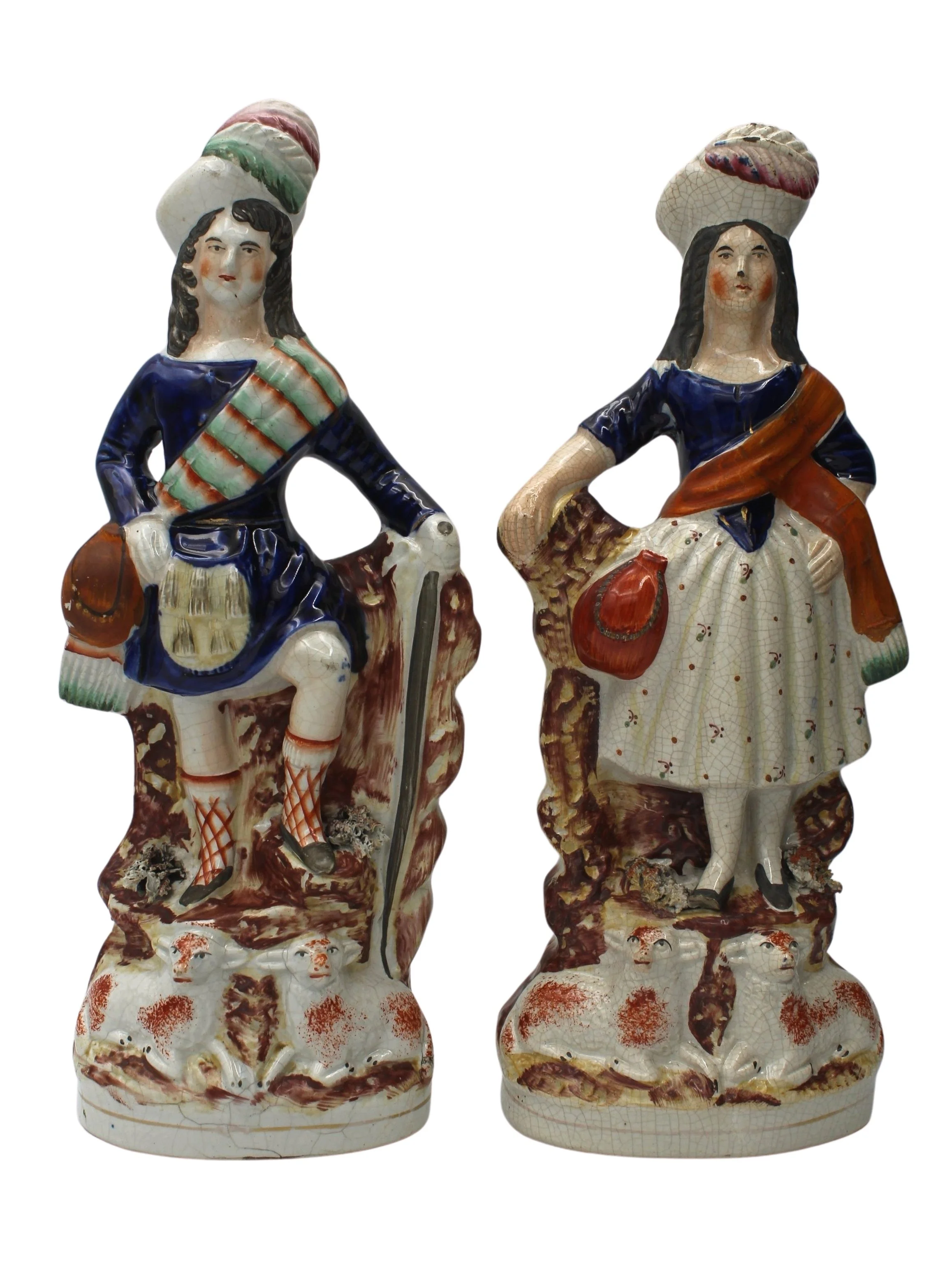 Two vintage porcelain figurines of a man and woman in traditional costumes, featuring detailed clothing, hats, and sheep at the base.