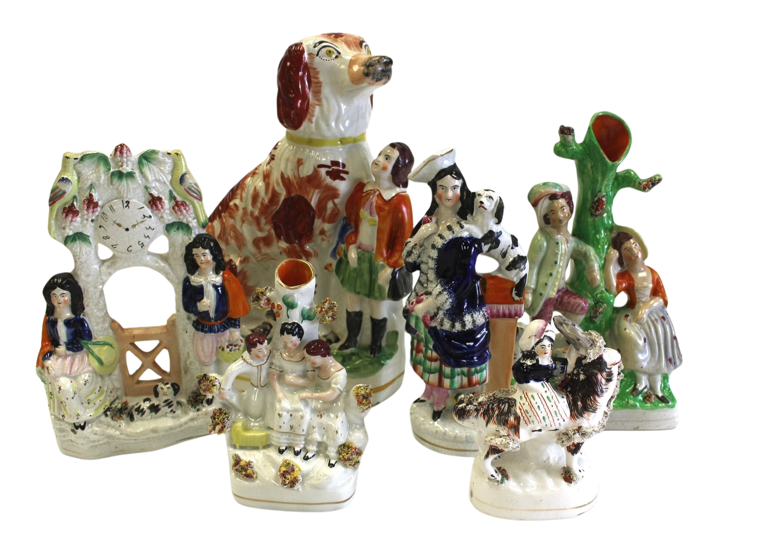 Collection of colorful ceramic figurines, including a large dog and figures of people in various poses, made in a traditional folk art style.