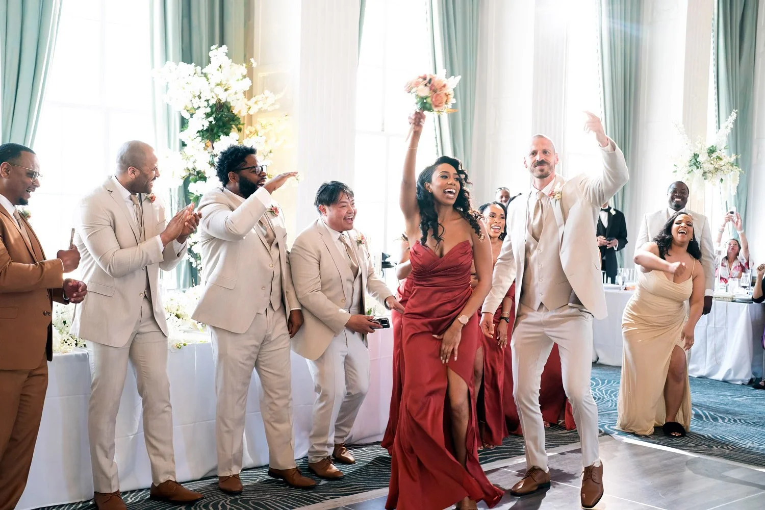 Bridesmaids and groomsmen cheer and dance during the grand entrance at a wedding reception at the Marriott Grand in downtown St. Louis