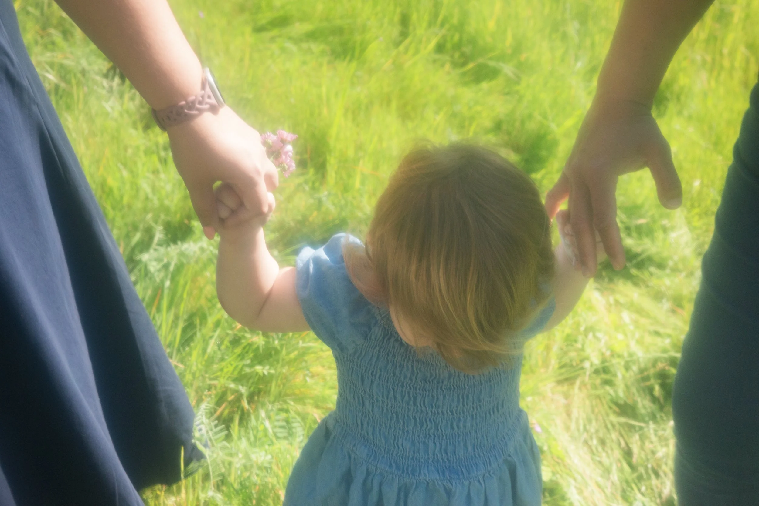 Lesbian family walking through meadow with child - Sacramento LGBTQ Family Photographer