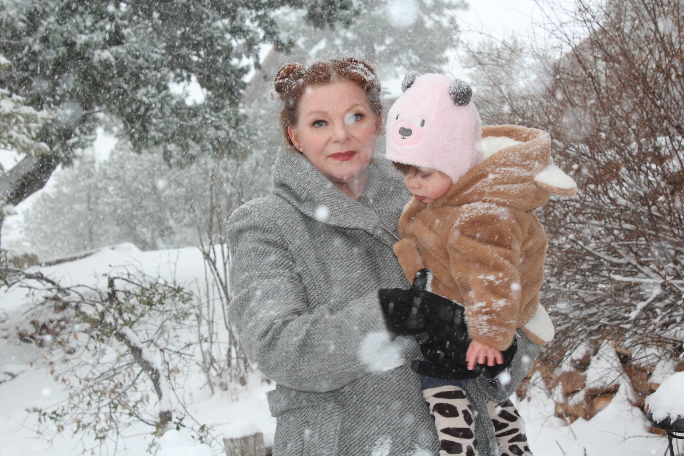 Blissom holding daughter and standing in snow.