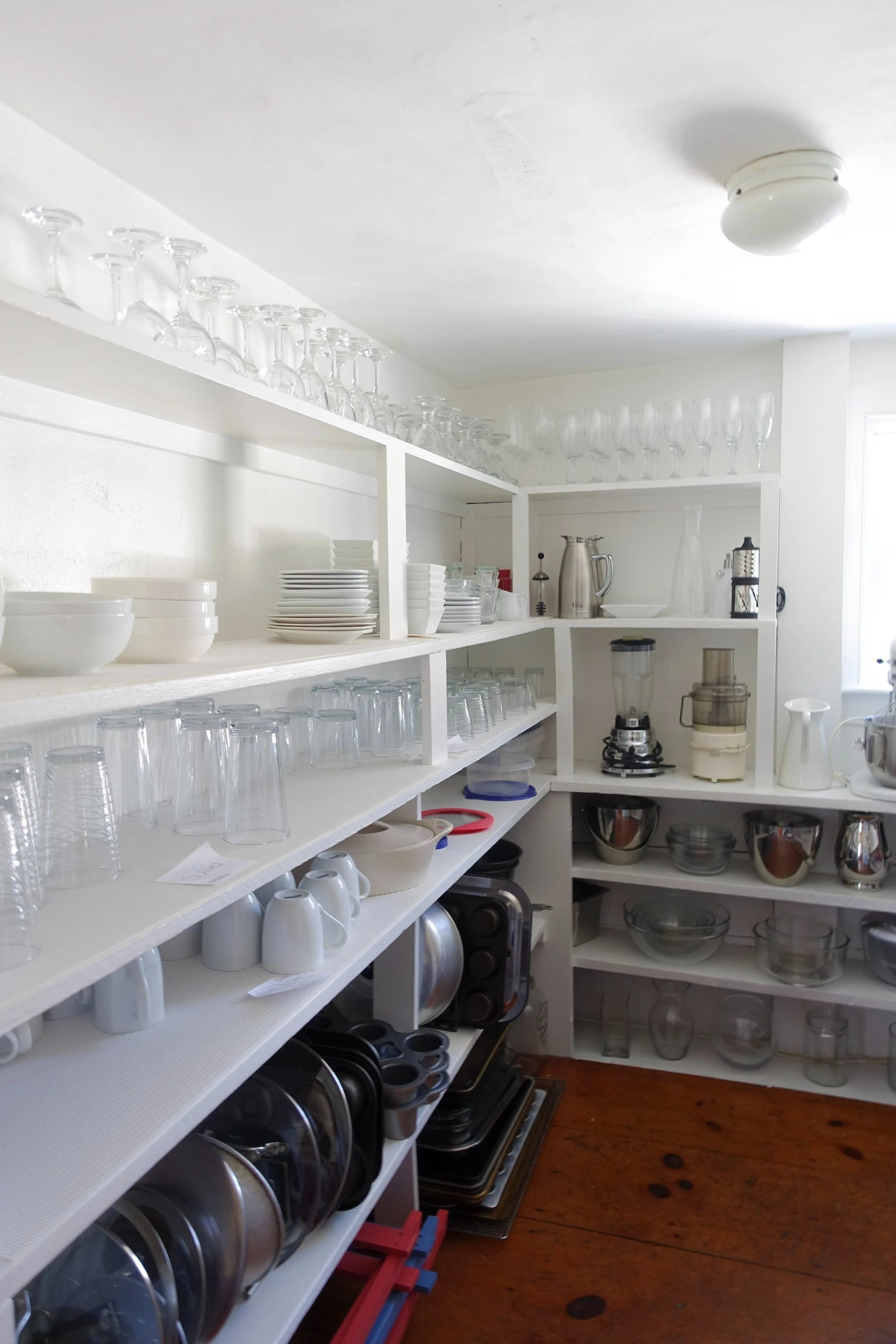 Kitchen shelves filled with glassware, dishes, and kitchen appliances.