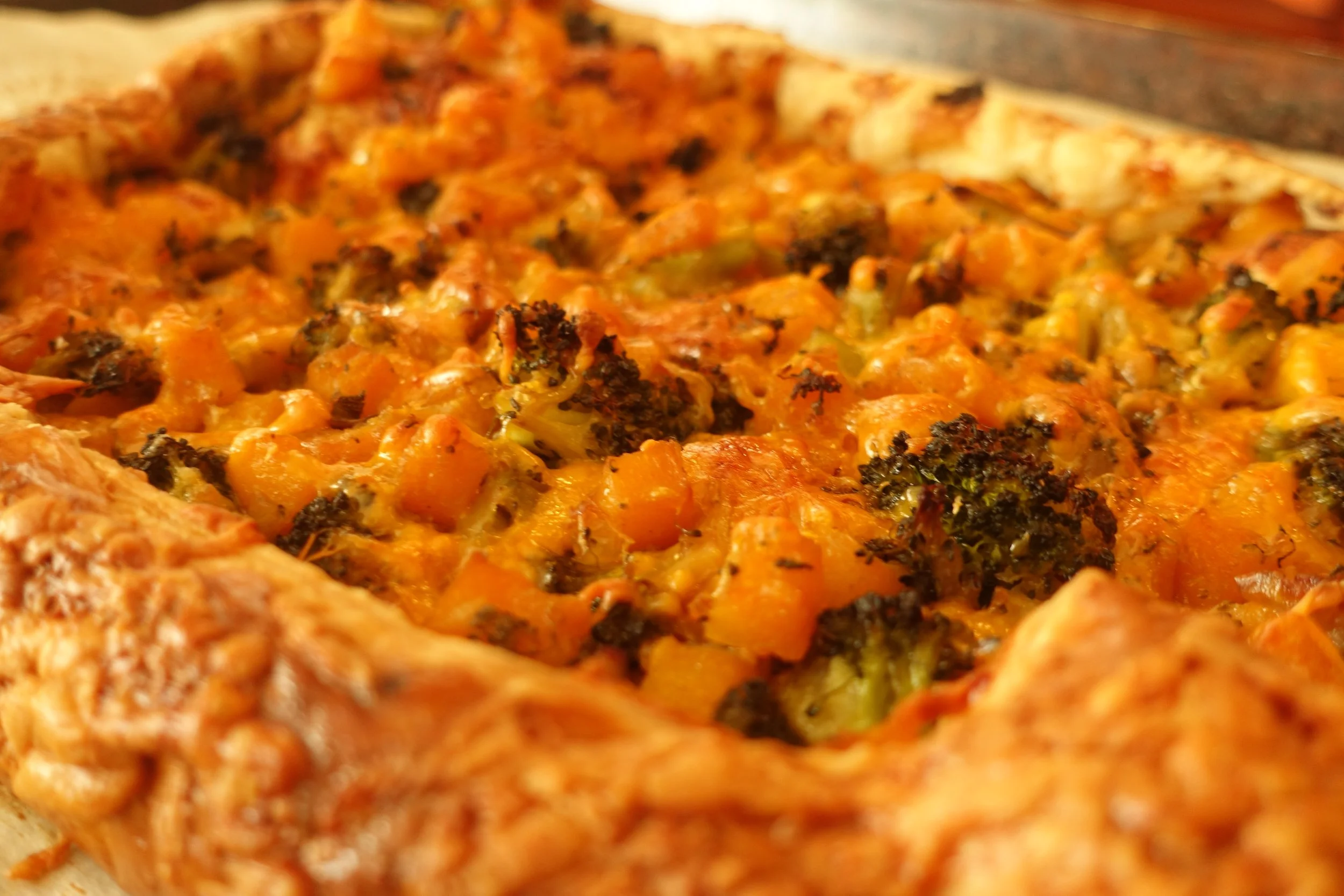 Close-up of a baked pizza with vegetables and cheese, showing a golden crust.