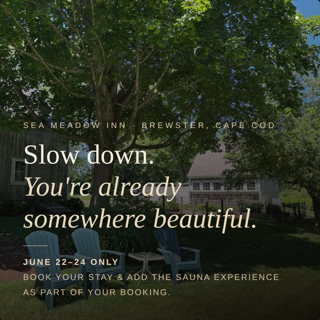 A backyard scene with a large tree, two blue Adirondack chairs, a small table, and a house in the background on a sunny day, promoting a stay at Sea Meadow Inn in Brewster, Cape Cod with a message to slow down and enjoy the moment.