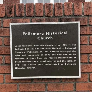 Plaque on brick wall describing Fellsmere Historical Church built around 1922, destroyed in 1954, restored and rededicated in 1994.