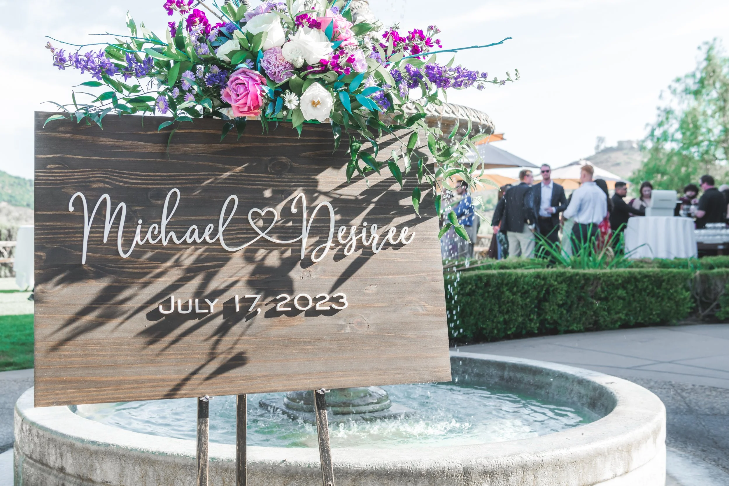 Wedding sign with the names Michael and Grace, decorated with flowers, at an outdoor wedding event on July 17, 2023.