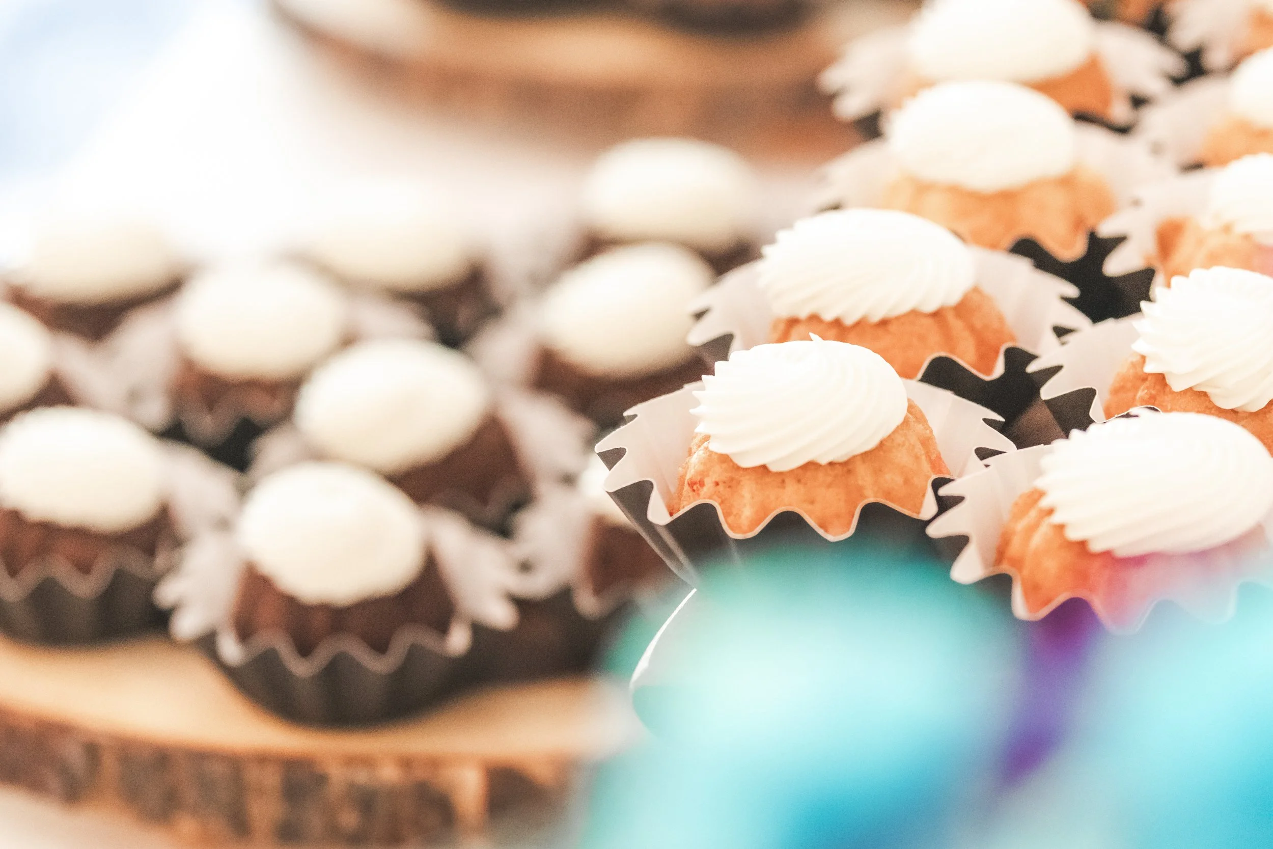 Close-up of cupcakes with white icing, placed in decorative cupcake wrappers, possibly for a celebration or event.